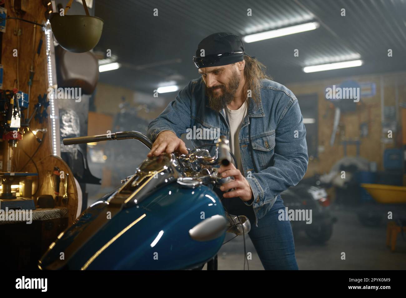 Reifer männlicher Biker, der sein neues Motorrad mit Garage untersucht Stockfoto