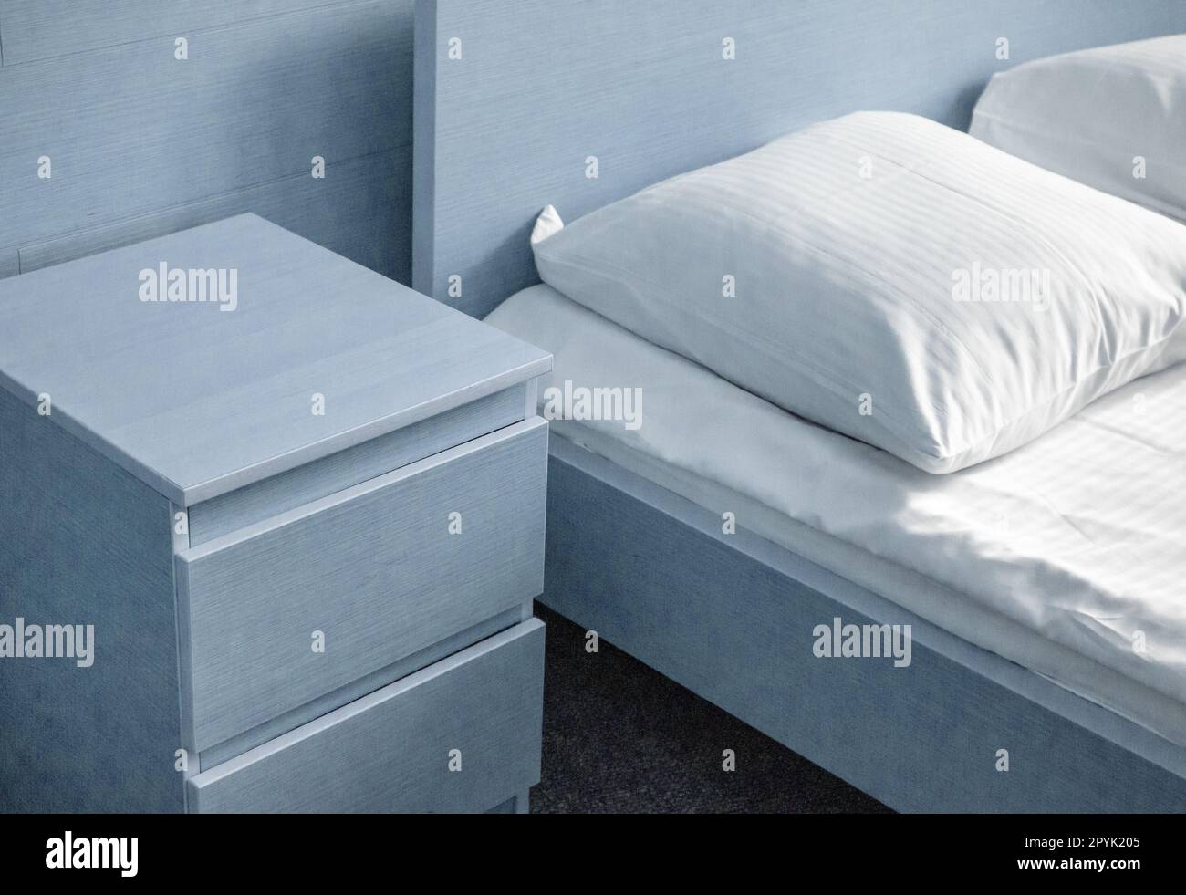 Hellblaue Tönung, Nahaufnahme des Bettes und Nachttischs, moderne Innenausstattung des Schlafzimmers im Hotel Stockfoto
