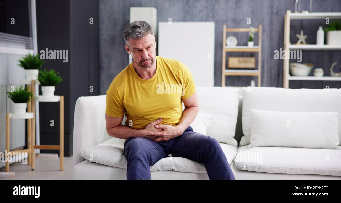 Mann Mit Magen Im Sitzen Stockfoto