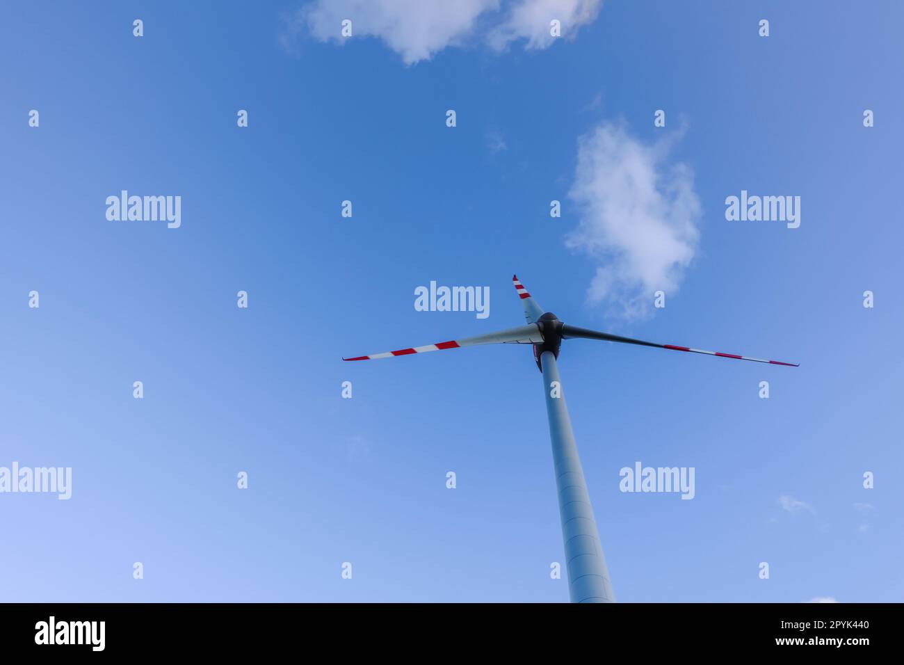 Hohe Windmühle und weiche Wolken am blauen Himmel für saubere Energie Stockfoto