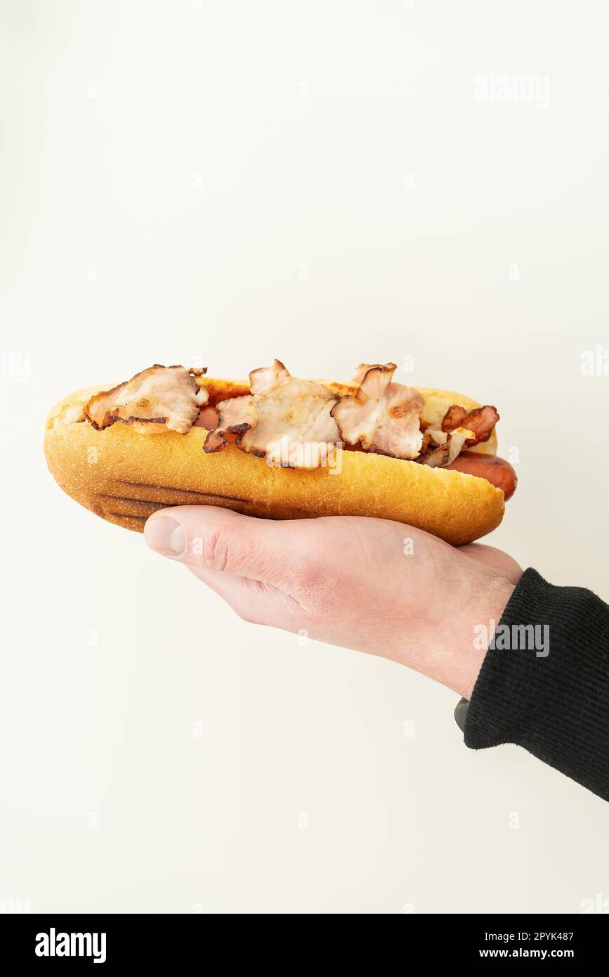 Kurzer Blick auf einen jungen Mann mit leckerem Hot Dog mit Senf und Ketchup auf weißem Hintergrund. Straßennahrung, Lieferung. Stockfoto