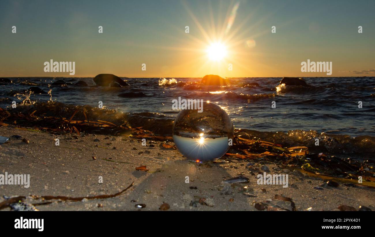 Der Strand und das Meer spiegeln sich in einer Kugel im Sand wider Stockfoto