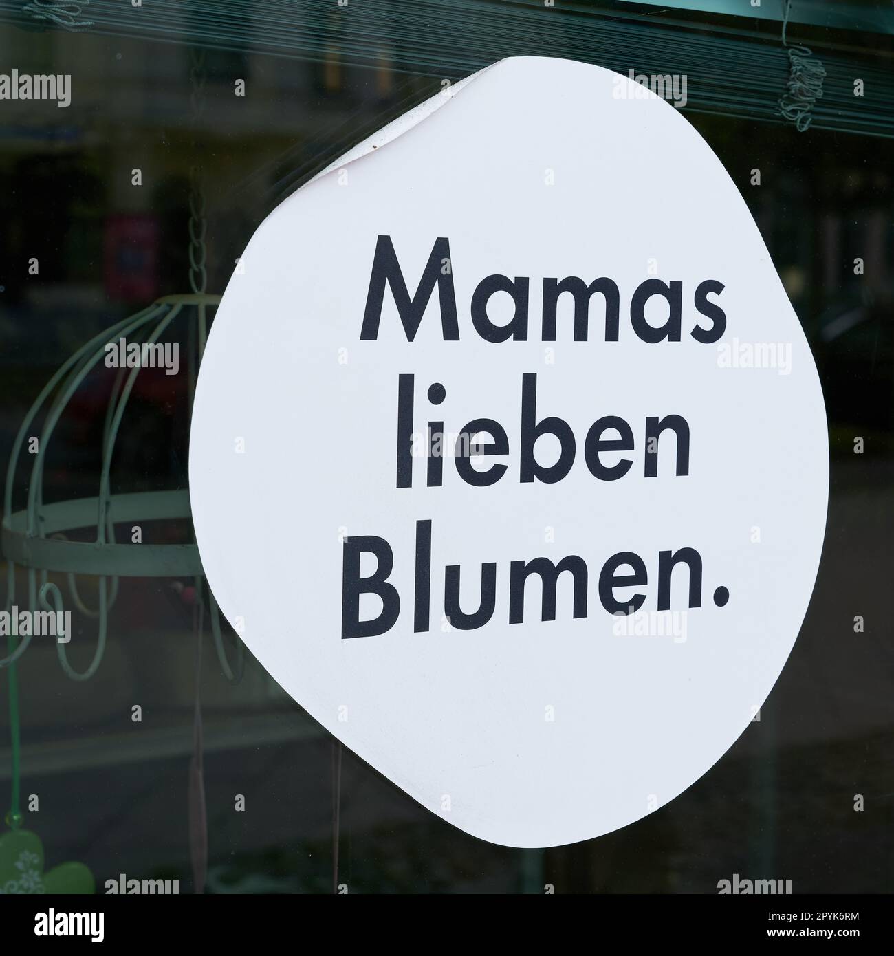 Aufkleber am Fenster eines Blumenladens mit der deutschen Inschrift Mamas lieben Blumen. Übersetzung: Mütter lieben Blumen Stockfoto