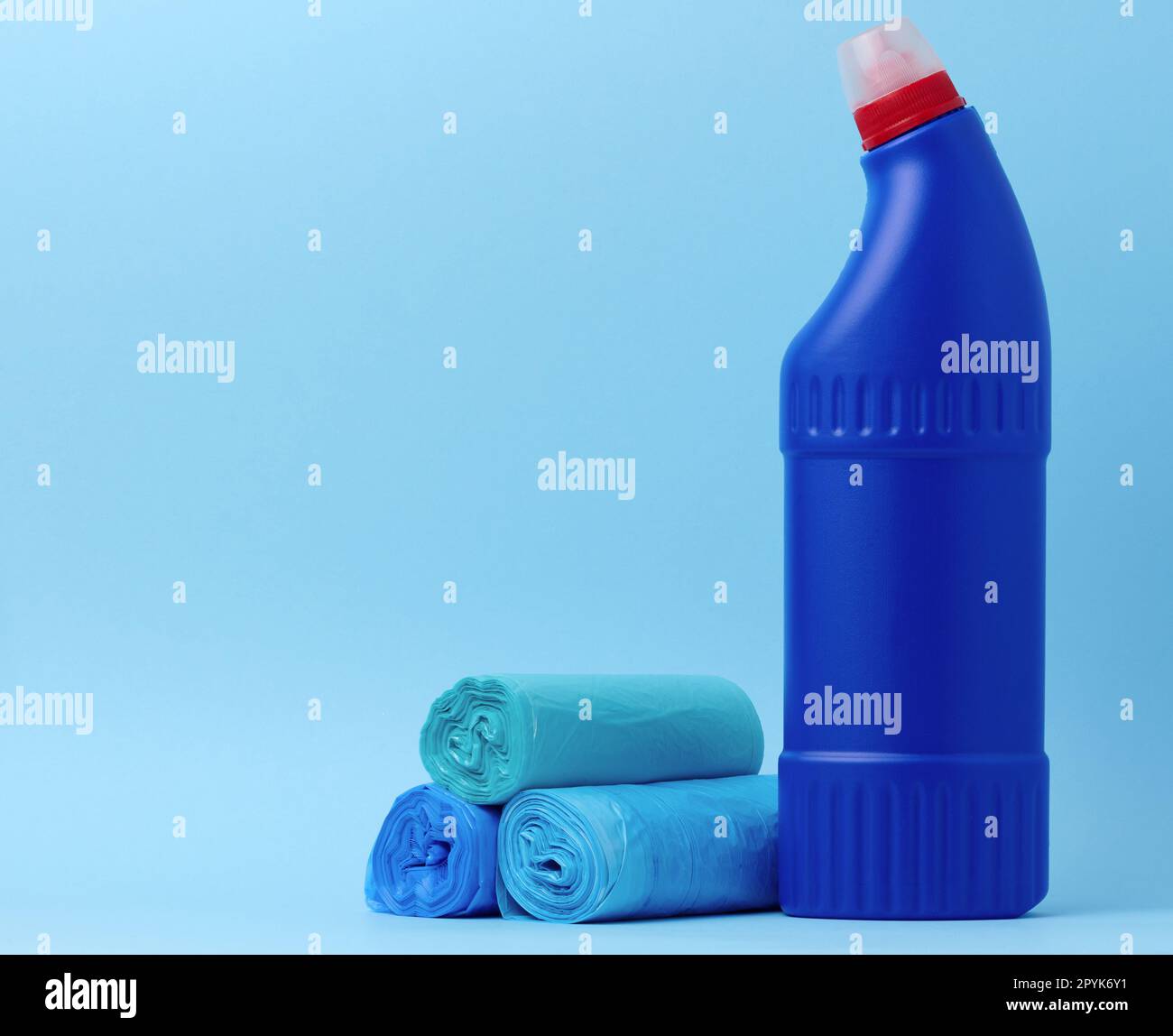 Müllsäcke und eine blaue Flasche mit Reinigungsmittel auf blauem Hintergrund Stockfoto