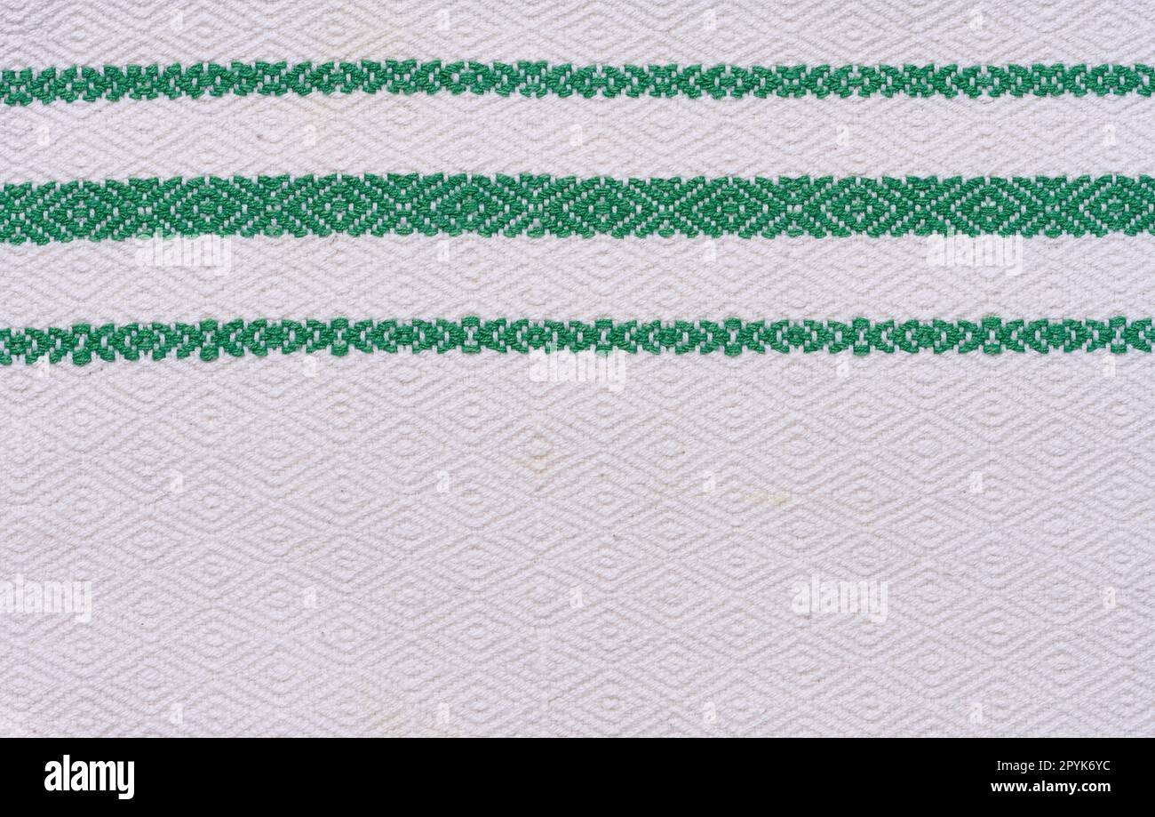 Ein Stück Baumwollstoff zur Herstellung von Tischdecken und Küchenhandtüchern mit grünen Stickerelementen Stockfoto