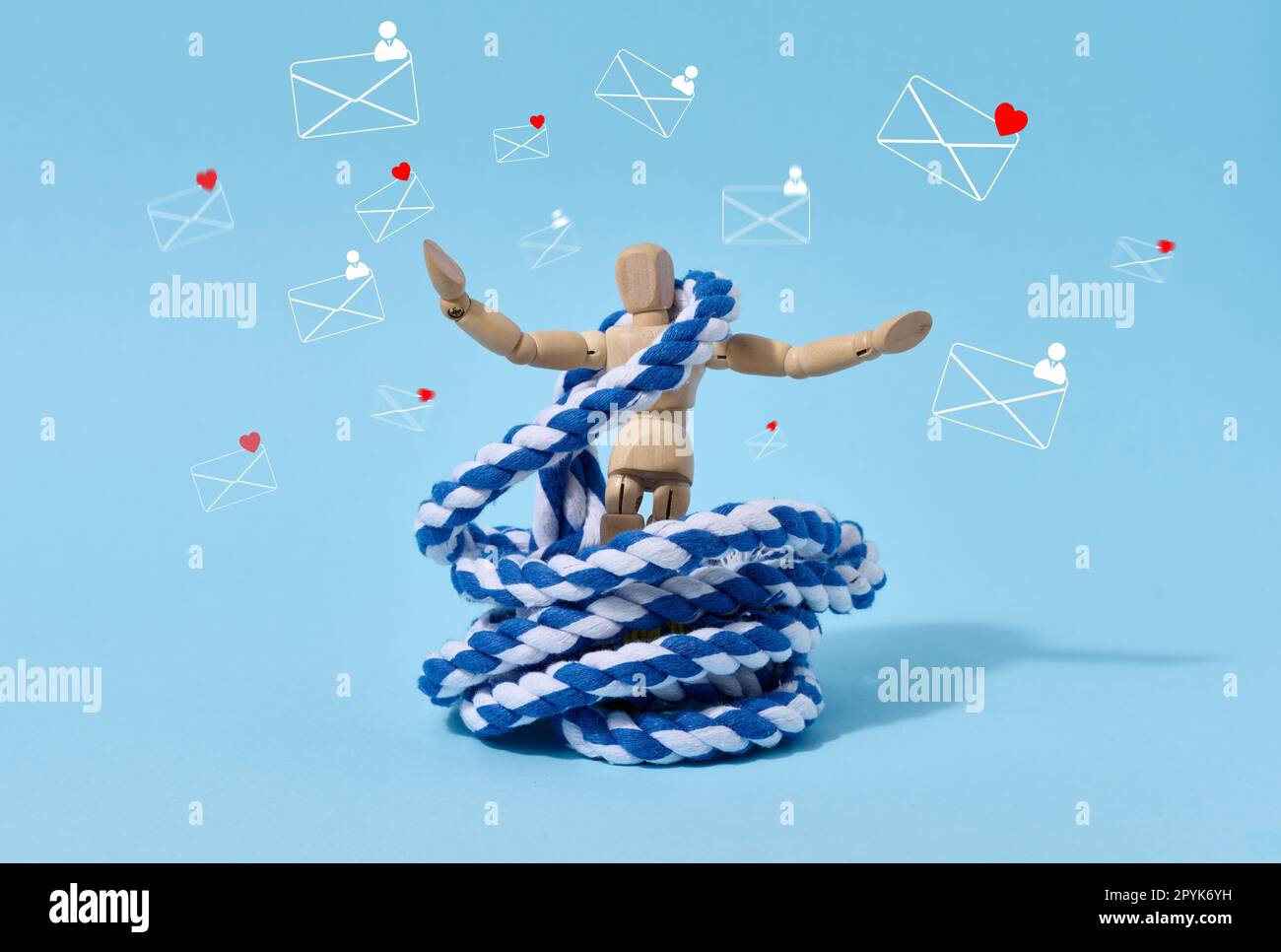 Eine Schaufensterpuppe aus Holz entwirrt Seile und Buchstabensymbole auf blauem Hintergrund. Der Begriff der Suchtbefreiung aus sozialen Netzwerken Stockfoto