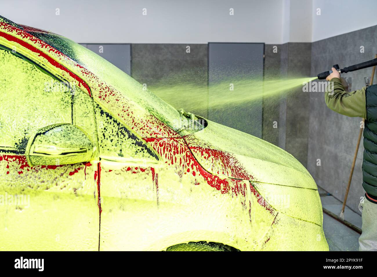 Besprühen von Autos mit grünem Schaum, chemische Reinigung und Waschen von Autos in der Garage Stockfoto