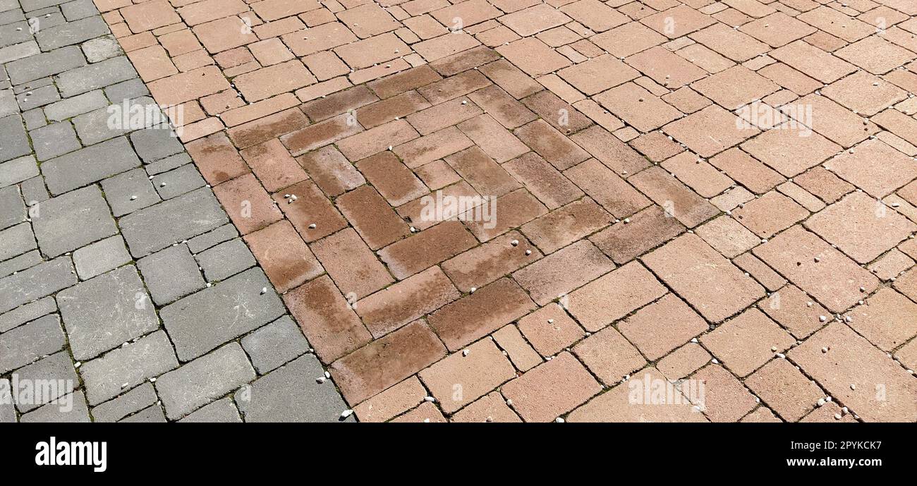 Kopfsteinpflasterstraße der Altstadt, gesäumt mit quadratischen und rechteckigen Steinfliesen in chaotischer Weise. Sanfte Beige- oder Gelbtöne. Die Textur des Steins. Geometrisches Muster Stockfoto