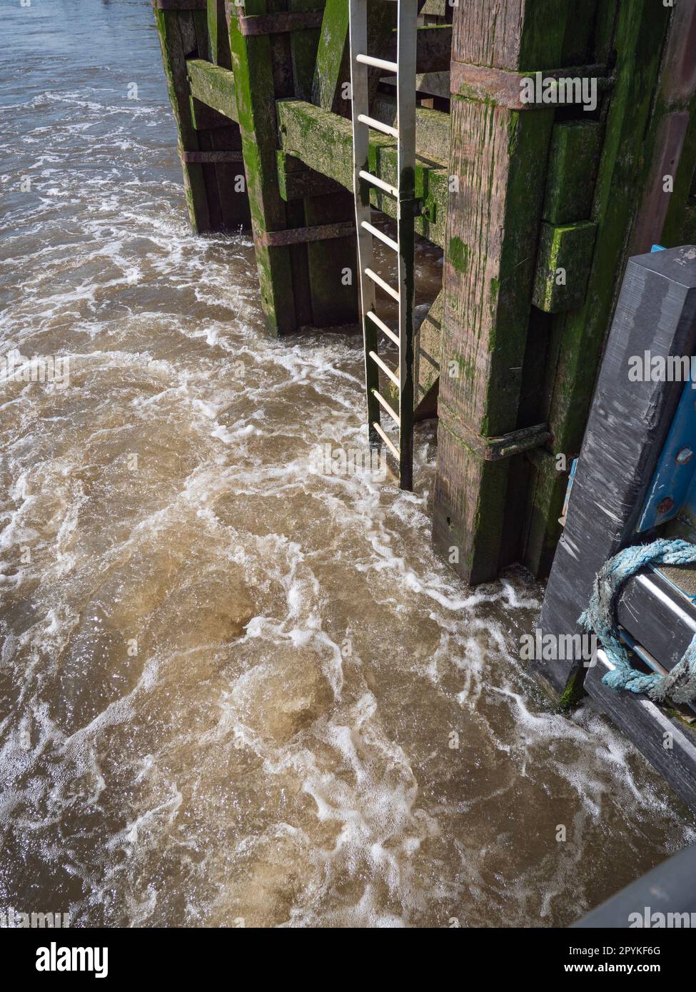 Das wirbelnde Wasser eines Flusses auf einem Steg mit einer eisernen Treppe, die ins Wasser führt Stockfoto