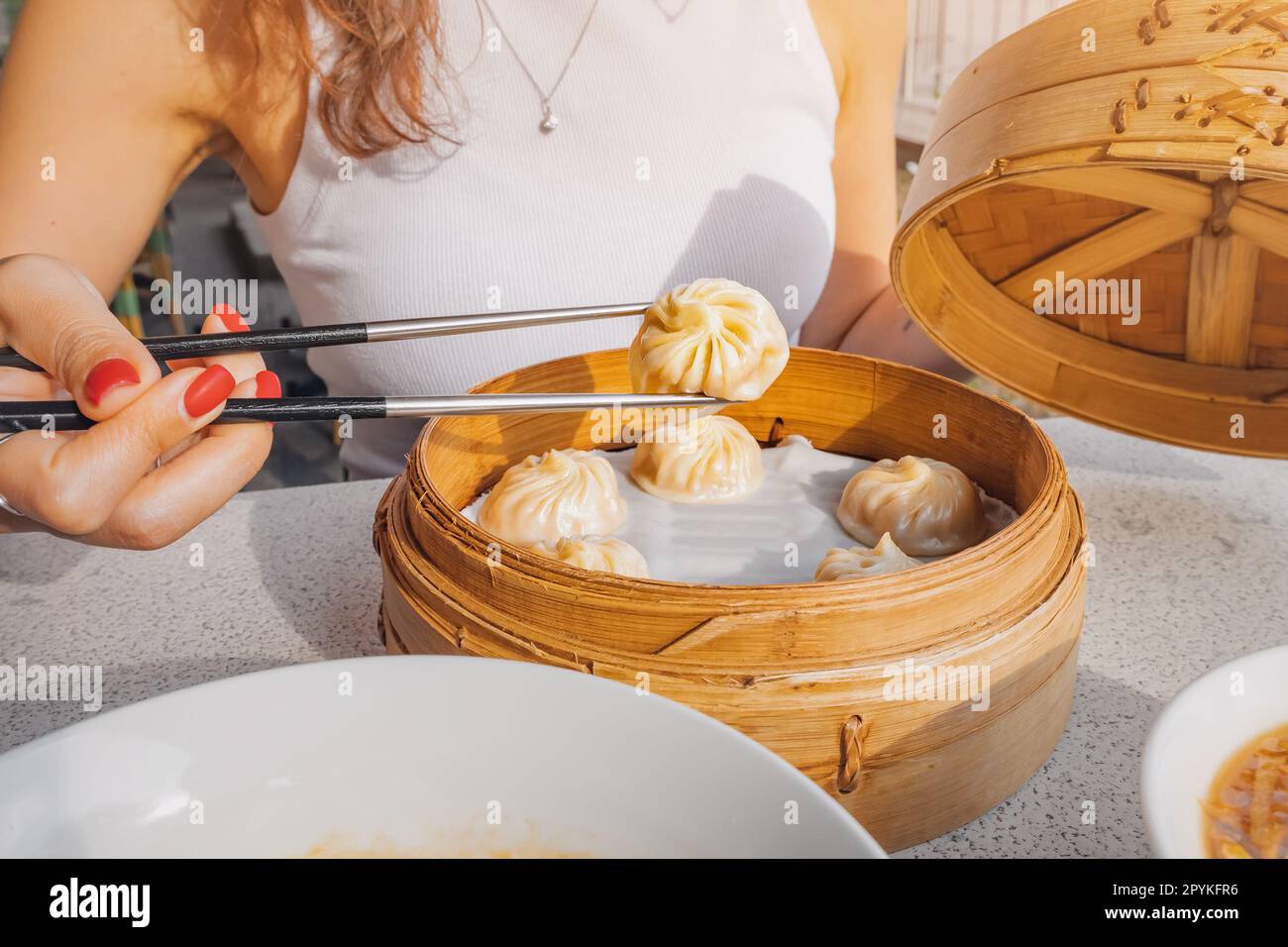 Mädchen mit Stäbchen, die köstliche, traditionelle chinesische ... Mädchen mit Stäbchen, die köstliche, traditionelle chinesische ...