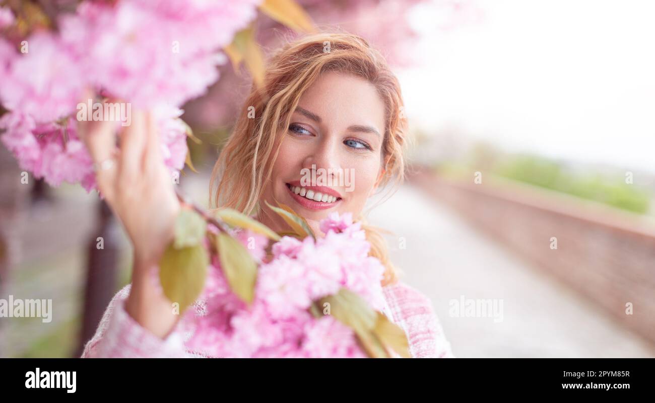 Wunderschöne 30s-jährige Weiße, die im Frühling Kirschblüte hält, draußen Stockfoto