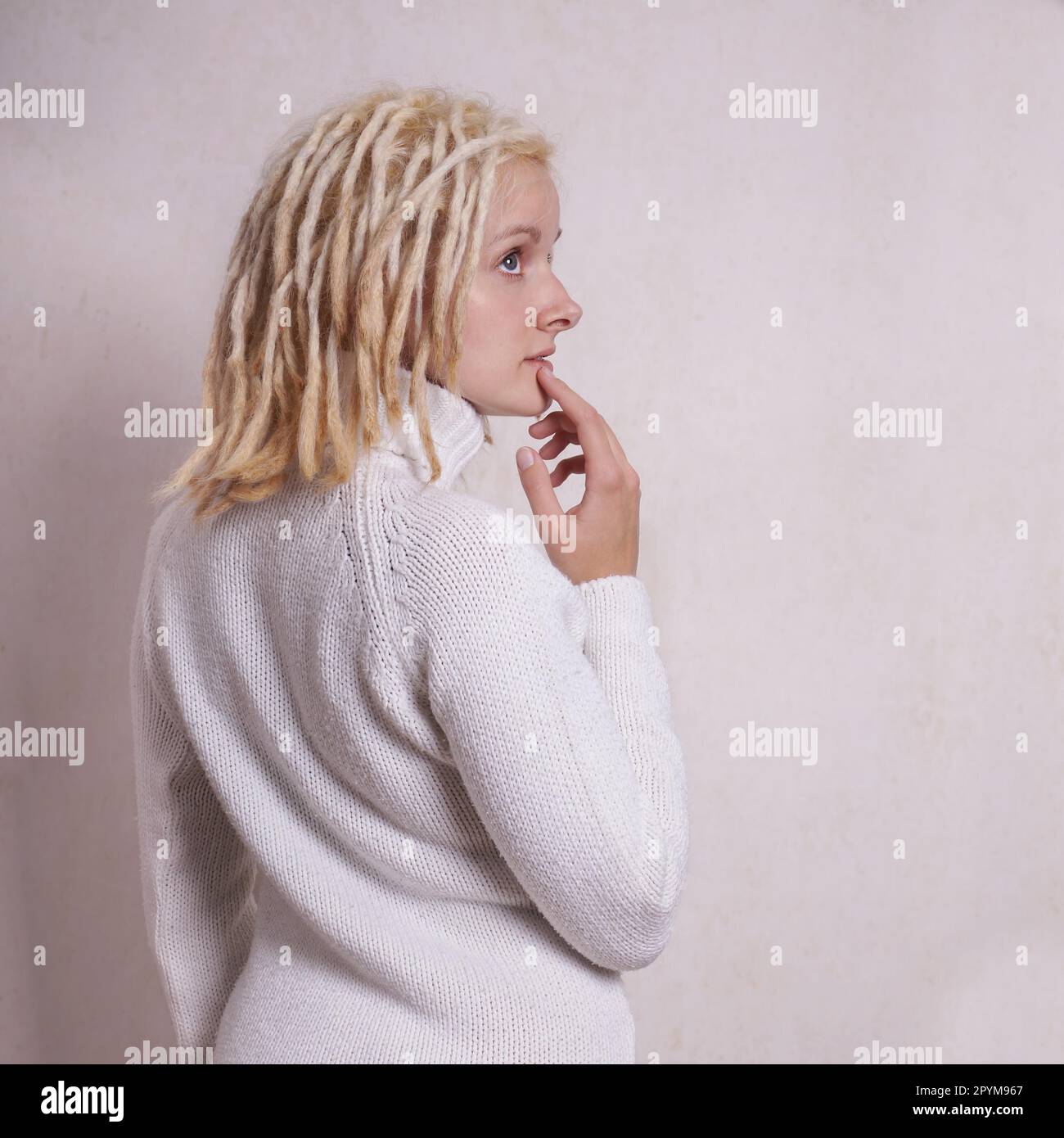 Nachdenkliche junge Frau mit blonden Dreadlocks auf der Seite suchen Stockfoto