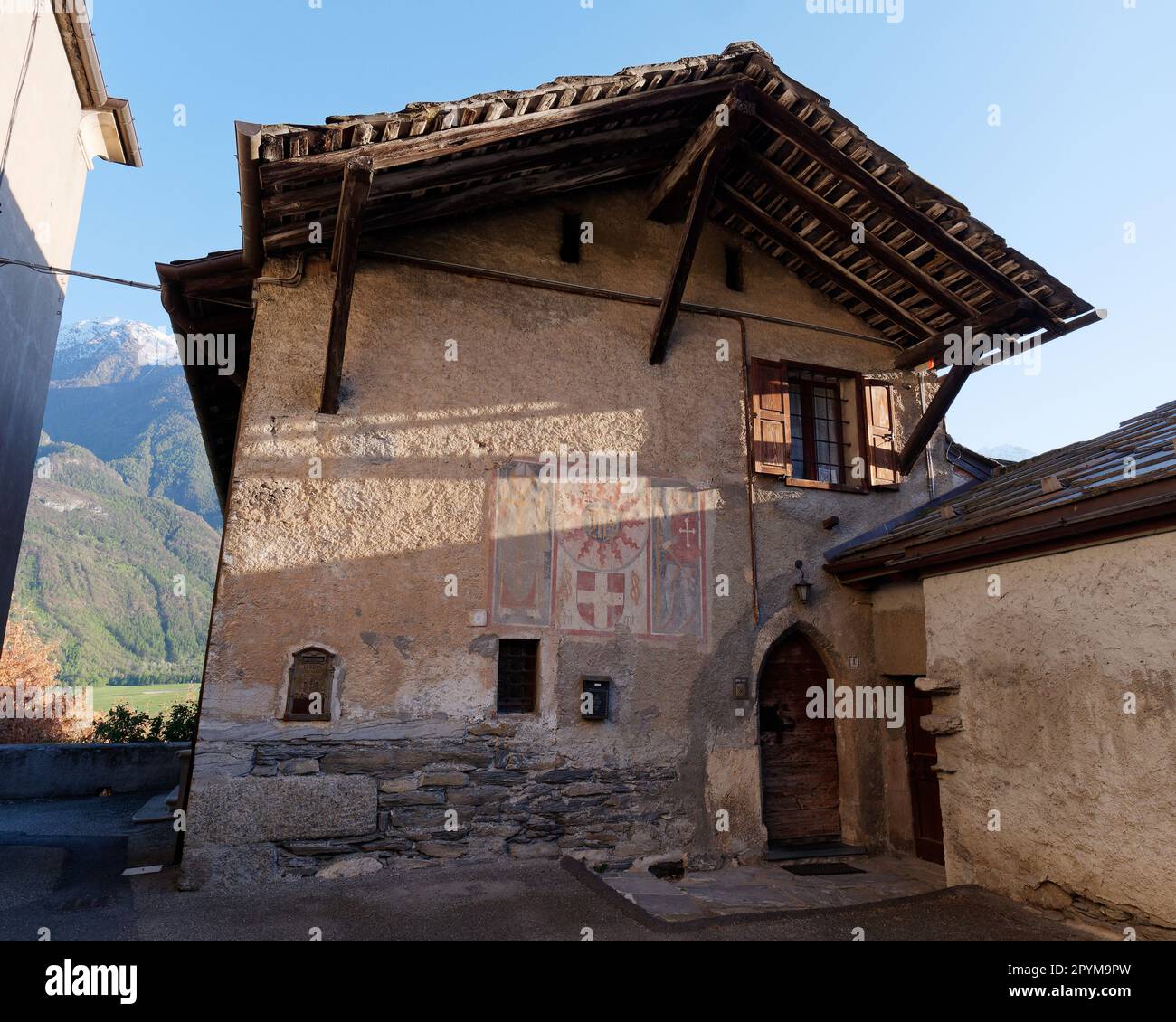 Historisches Steingebäude neben der Diemoz-Kirche (links auf dem Bild) mit Holztür und -Dach. Aosta Valley, NW Italien Stockfoto