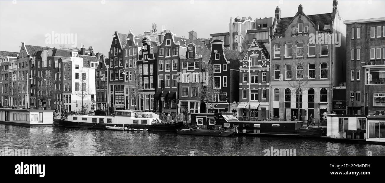 Traditionelle holländische Architektur am Kanal mit verankerten Booten in Schwarz und Weiß, Amsterdam, Holland. Stockfoto