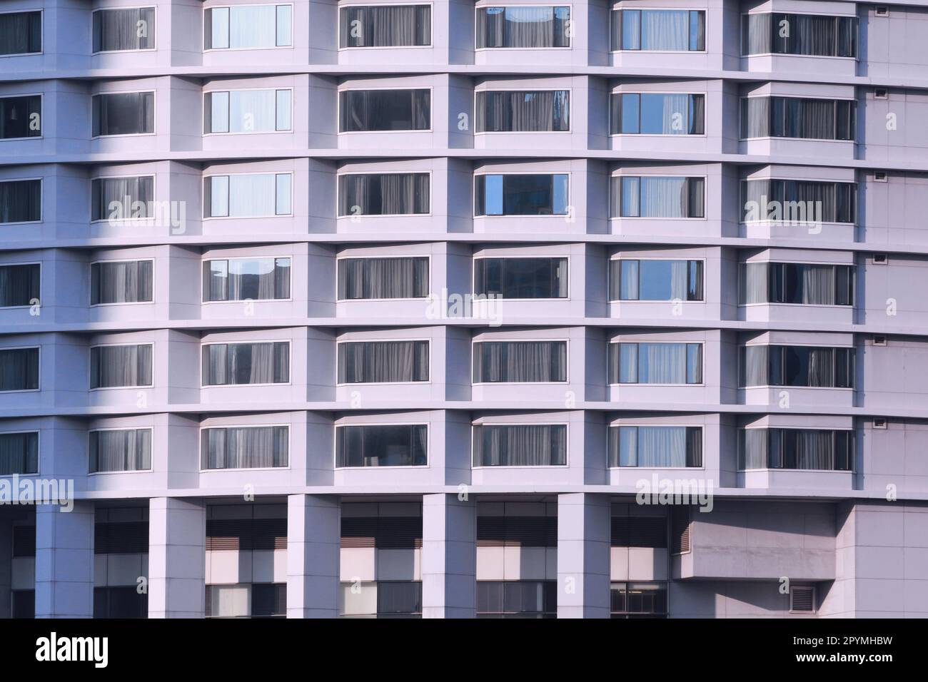Hoher Gebäudehintergrund, Seite des Gebäudes mit Fenstern und Türen für Design im Arbeitshintergrund Konzept. Stockfoto