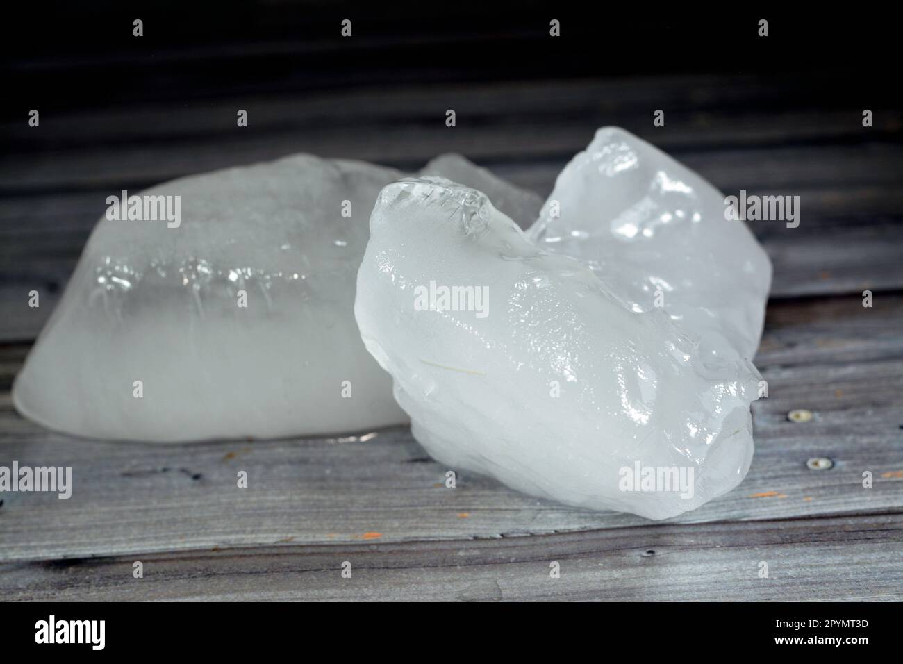 Eisstücke aus dicken festen Teilen gefrorenen Wassers, isoliert auf Holzhintergrund, selektiver Fokus von Frosteisstücken, die für Erfrischungen verwendet werden könnten Stockfoto