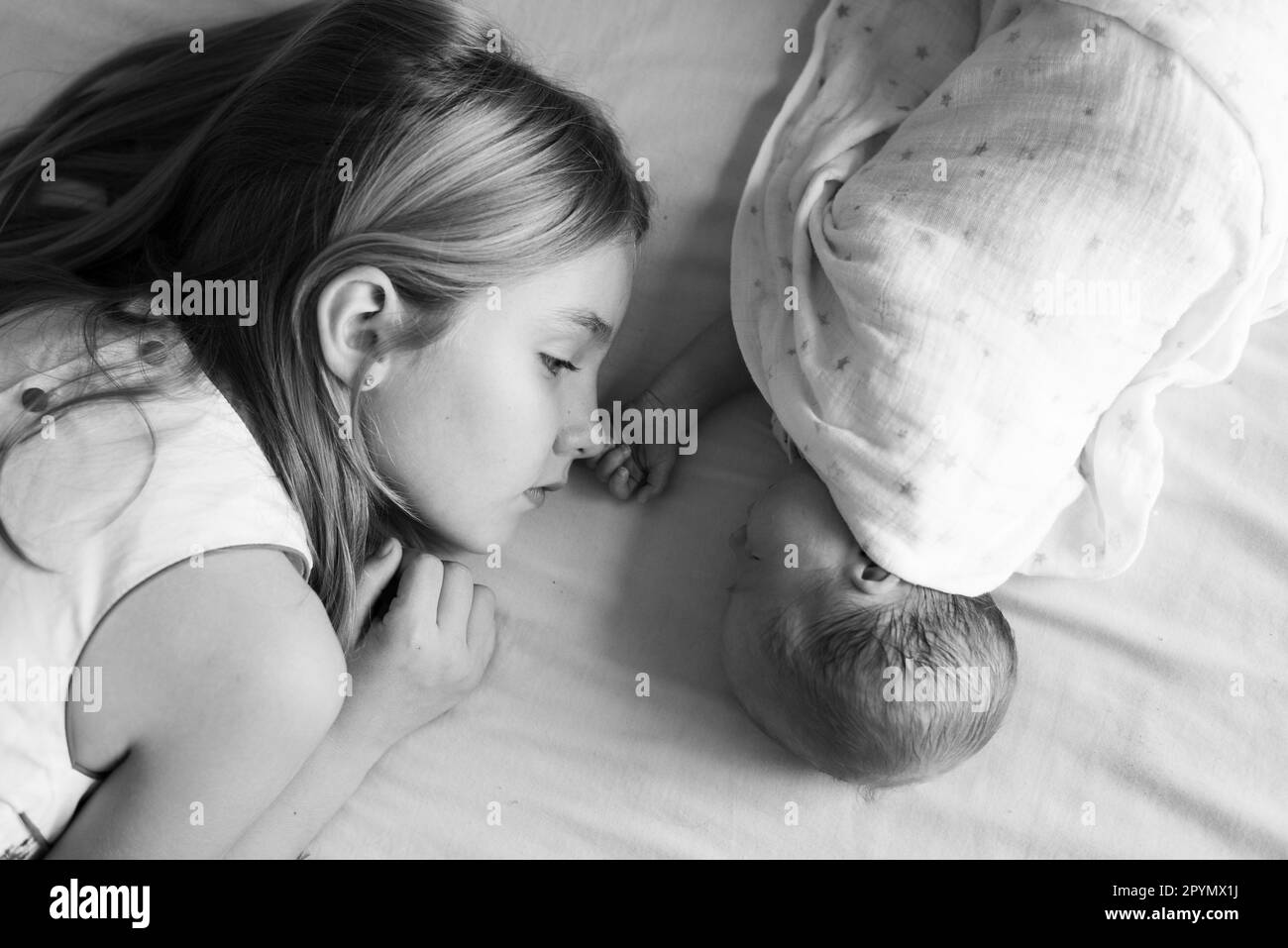 Eine Schwester, die während der Windelwechselzeit auf einem Wickeltisch mit ihrem Baby spielt und sich mit ihrem Geschwister verbindet Stockfoto