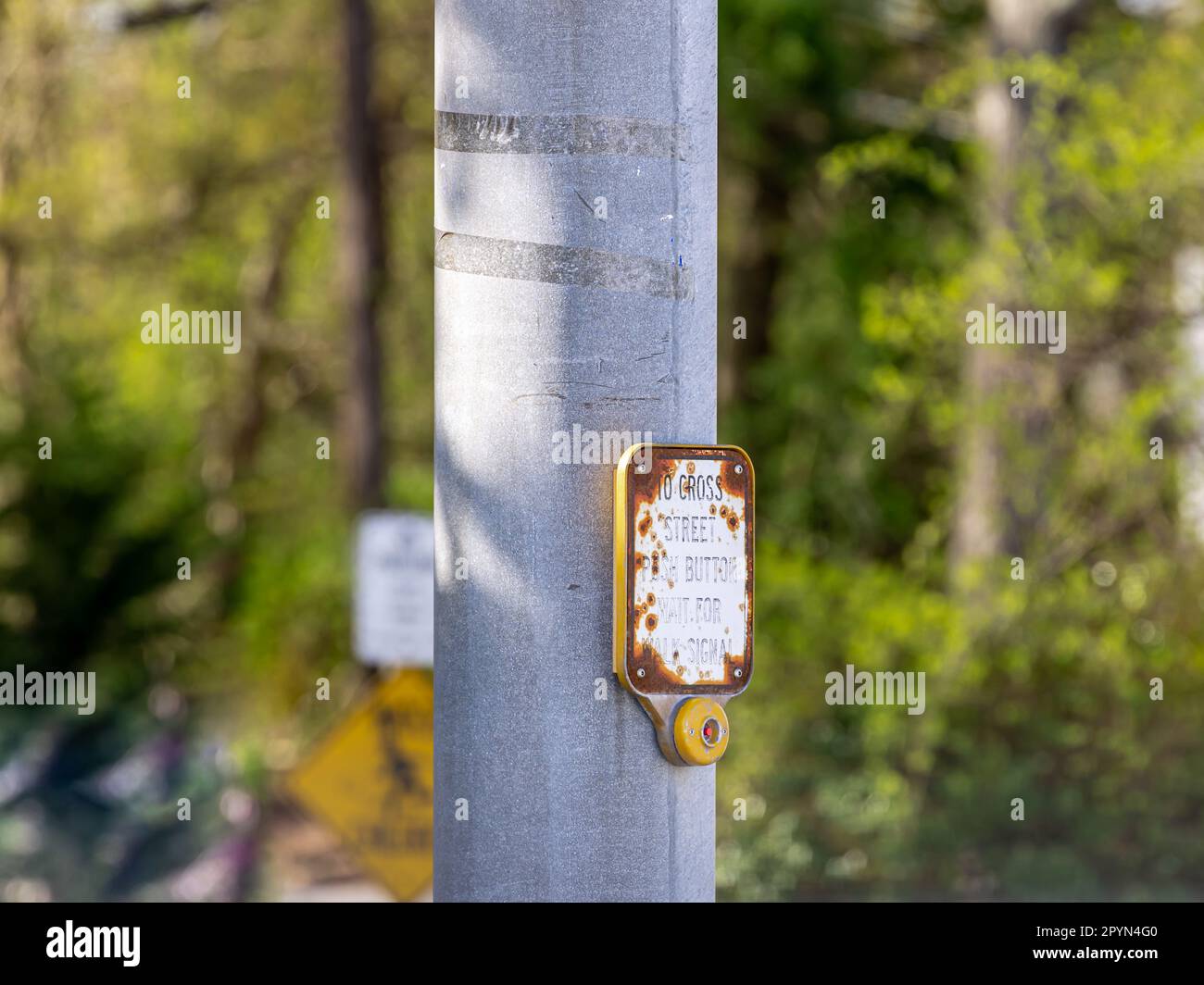 Detailbild eines alten Schildes und Druckknopfes, das die Ampel aktiviert, damit jemand die Straße überqueren kann Stockfoto