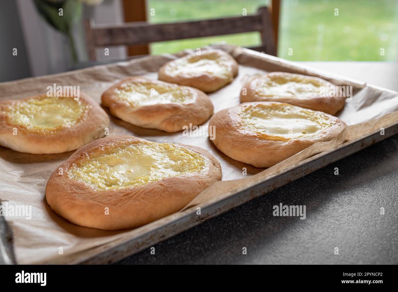Frisch gebackenes Hefe-Gebäck mit saurer Sahne, Vanille-Pudding-Füllung auf einem Backtuch Stockfoto