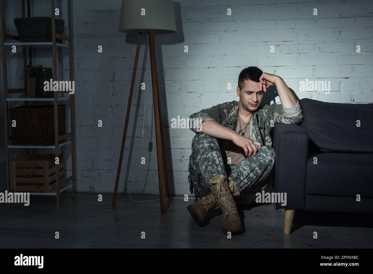 Deprimierter Militärveteran in Uniform, der zu Hause auf dem Boden sitzt, Börsenbild Stockfoto