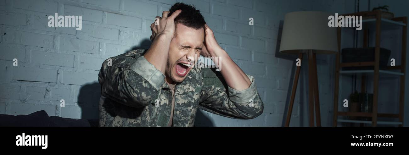 Wütender Soldat mit psychischer Störung, der nachts zu Hause schreit, Banner, Börsenbild Stockfoto