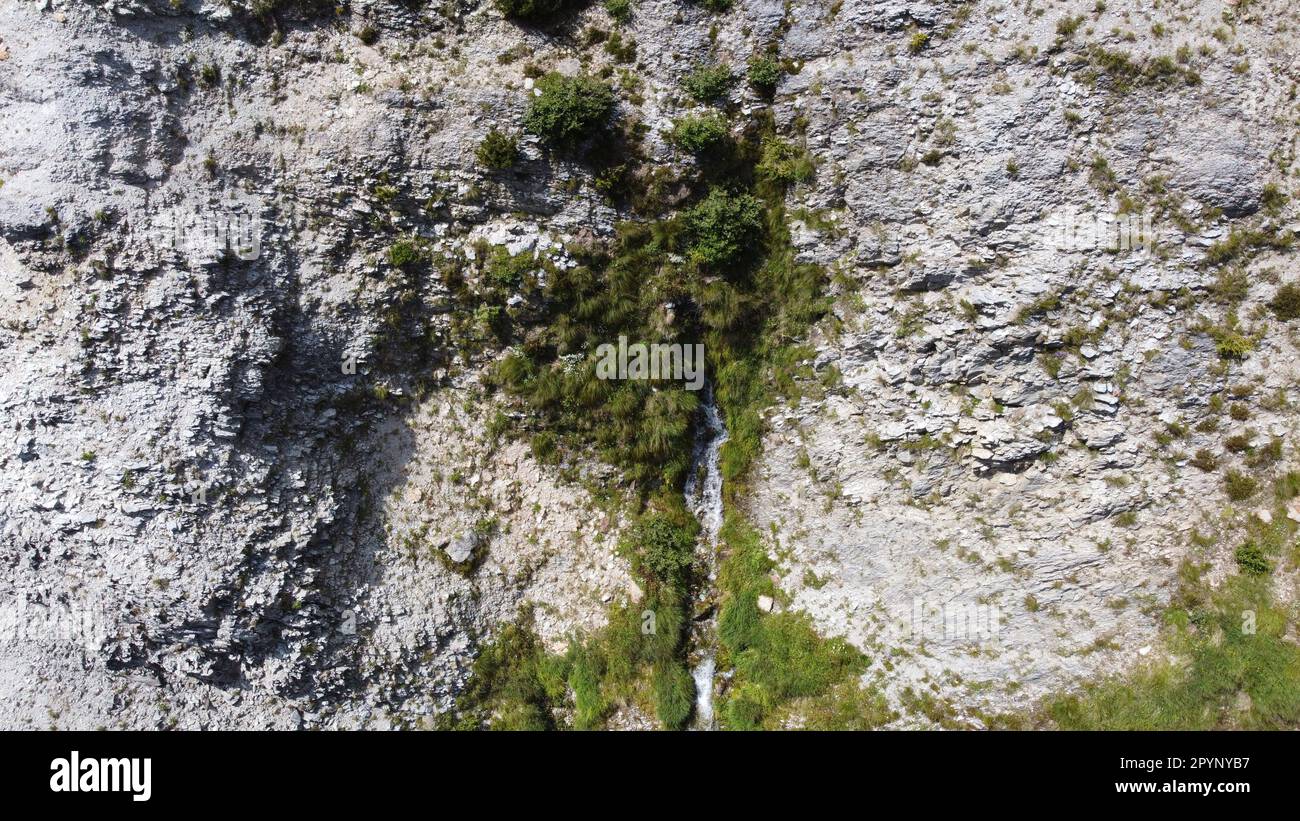 Wasserquelle, welche Handschuhe aus dem Berg austritt und über einen spektakulären Wasserfall in Tal fließt Stockfoto