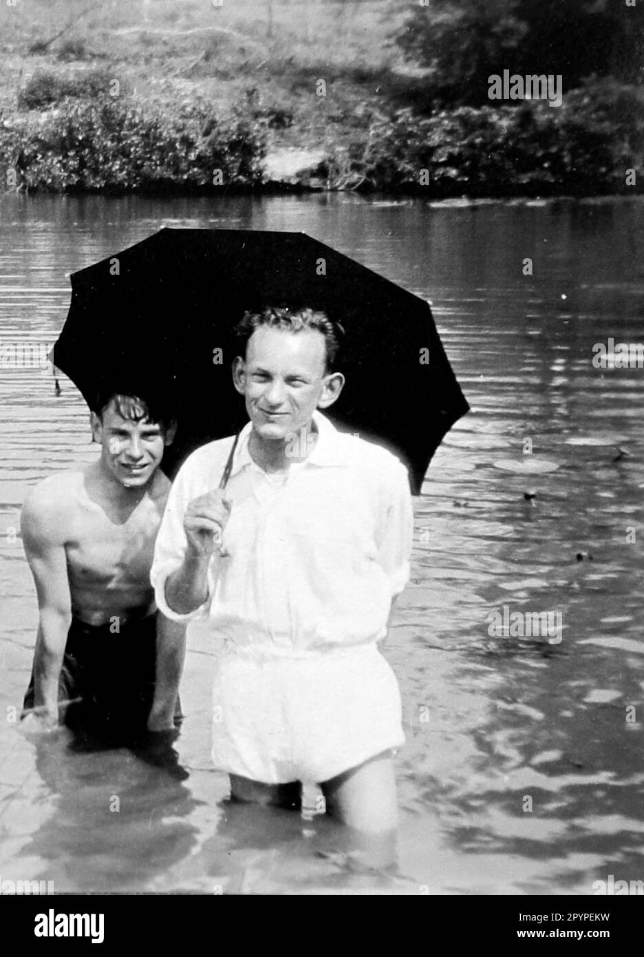 Zwei Männer im tiefen Wasser mit einem Regenschirm, c1928. Aus einem einzigartigen Fotoalbum, das von K.W. zusammengestellt wurde Parkhurst, einem Landlager in Bolney (einer landwirtschaftlichen Gemeinde), West Sussex, England, das zwischen 1928 und 1930 ein regelmäßiges Ziel für eine Gruppe junger Männer war, darunter Mr. Parkhurst. Dies geschah während der Zeit der Großen Depression. Stockfoto