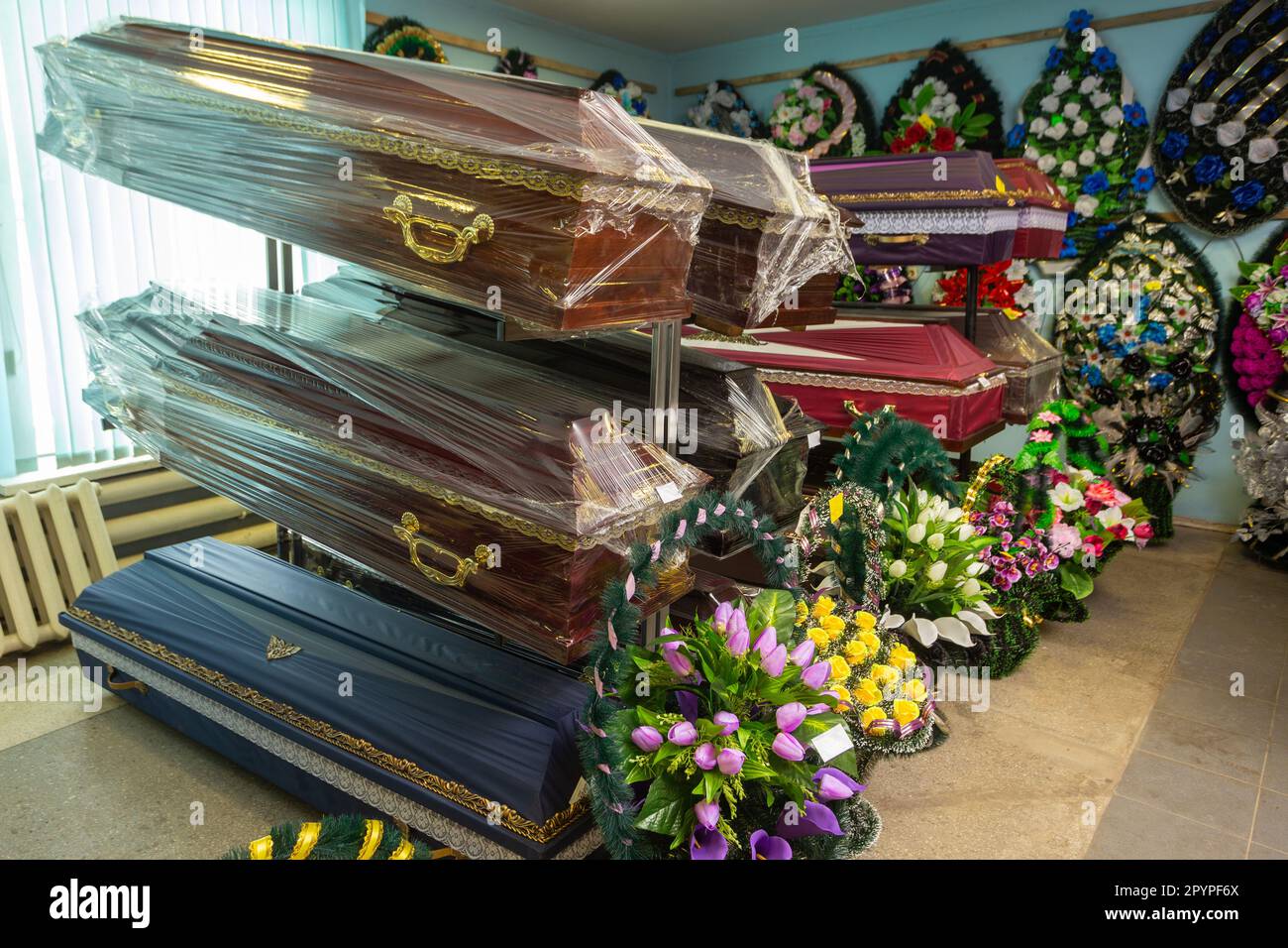 Innenraum des Raumes mit Bestattungszubehör. Geschäft mit Särgen, Beerdigungskränzen und Blumen. Stockfoto