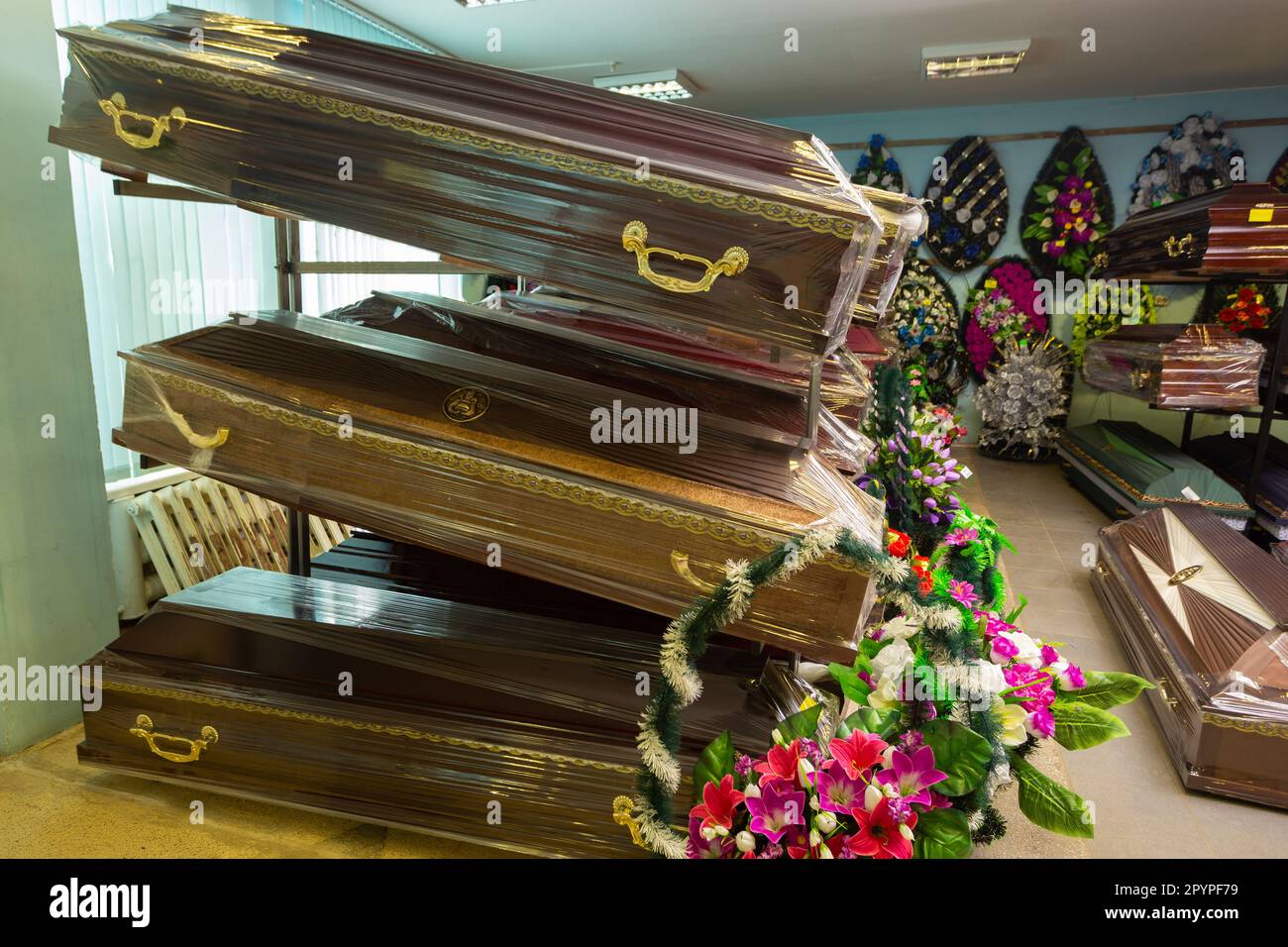 Innenraum des Raumes mit Bestattungszubehör. Geschäft mit Särgen, Beerdigungskränzen und Blumen. Stockfoto