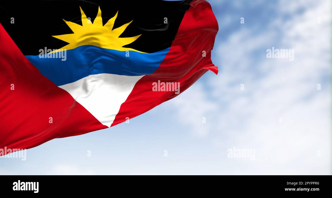 Antigua und Barbuda Nationalflagge winken an einem klaren Tag. Rotes Feld mit umgekehrtem Dreieck aus Schwarz, Blau, Weiß und aufgehender Sonne. Rendern der 3D-Darstellung Stockfoto