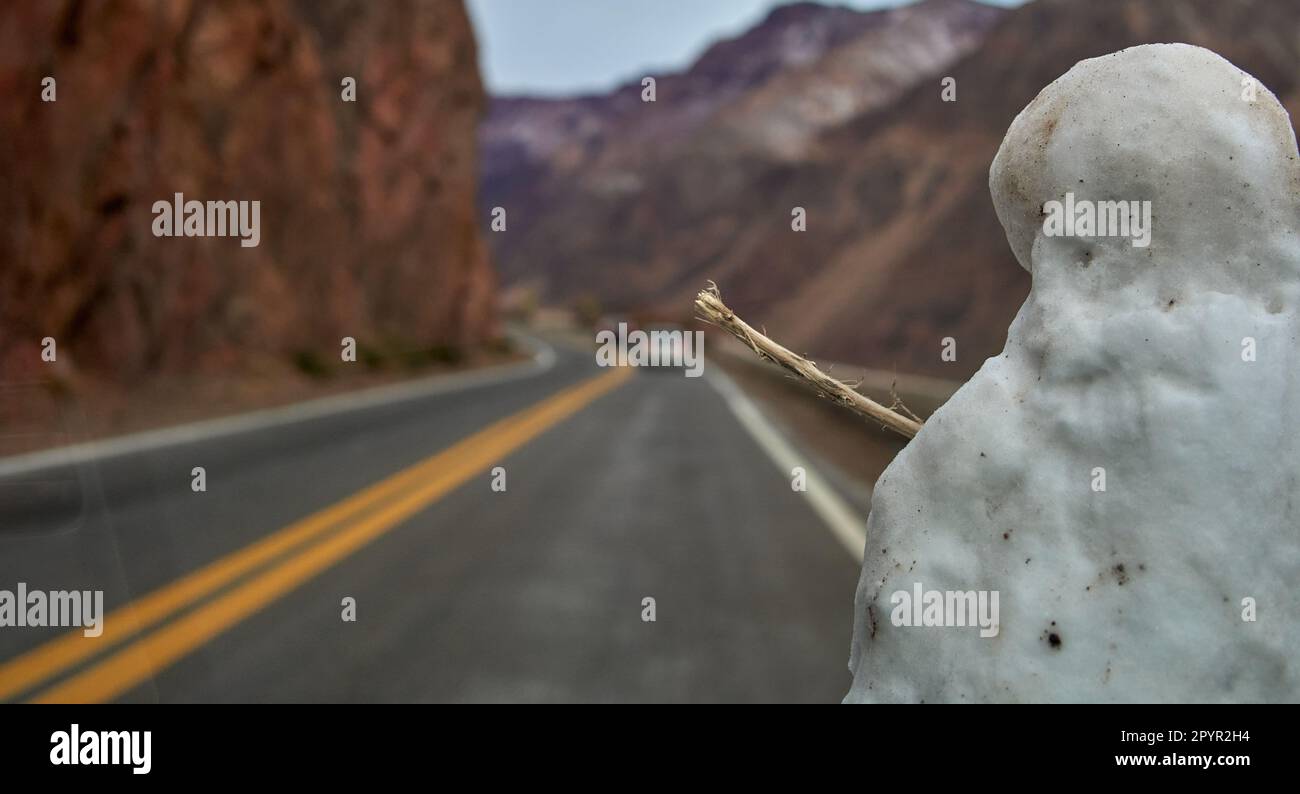 Ein halber Schneemann auf einem fahrenden Auto, der Bergstraßen in mendoza Argentina überquert. Sie ist vom Fahrzeuginnenraum aus zu sehen. Selektiver Fokus Stockfoto