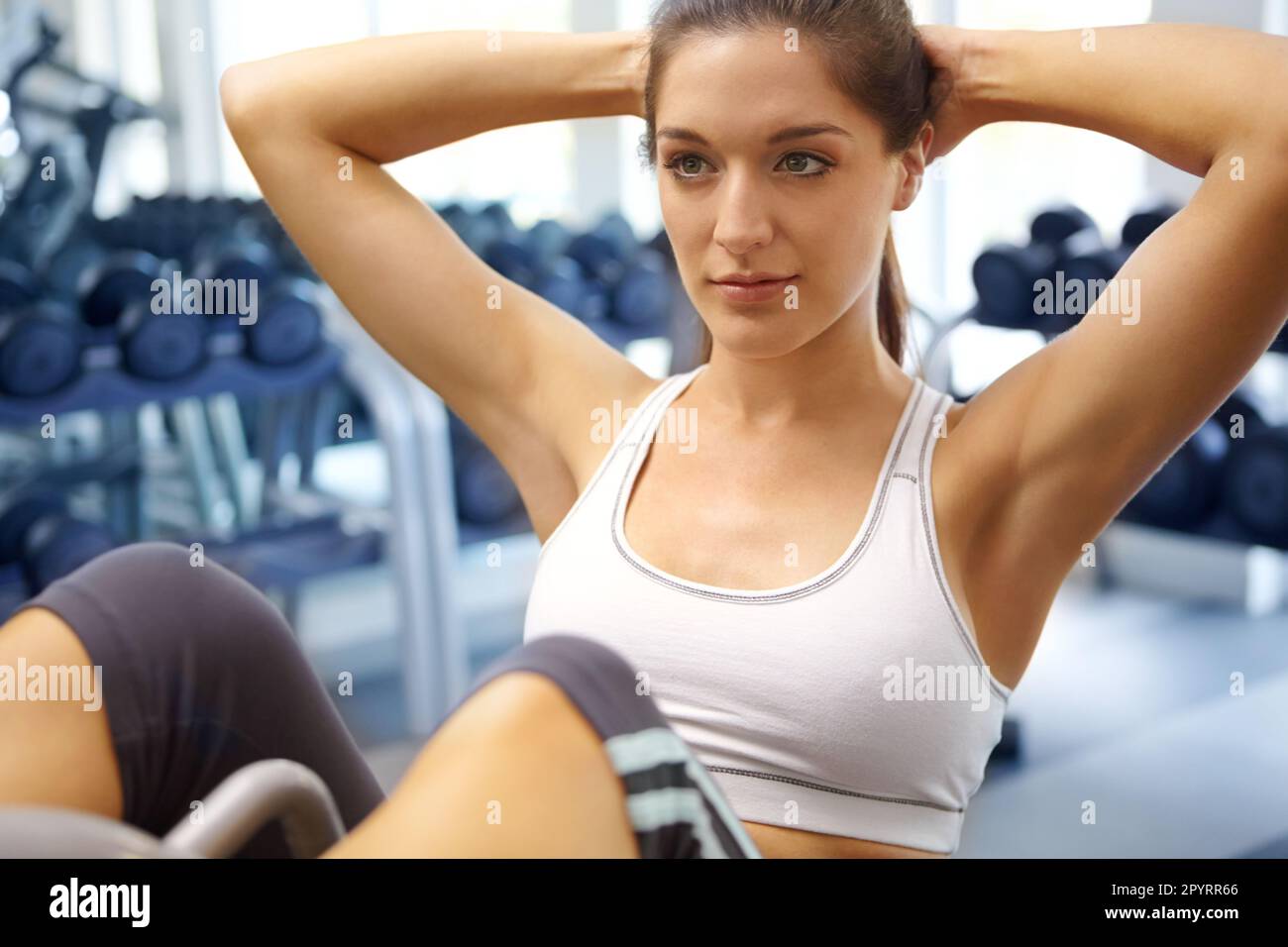 Sit-ups für einen starken Kern. Eine wunderschöne junge Frau, die im Fitnessstudio Sit-ups macht. Stockfoto