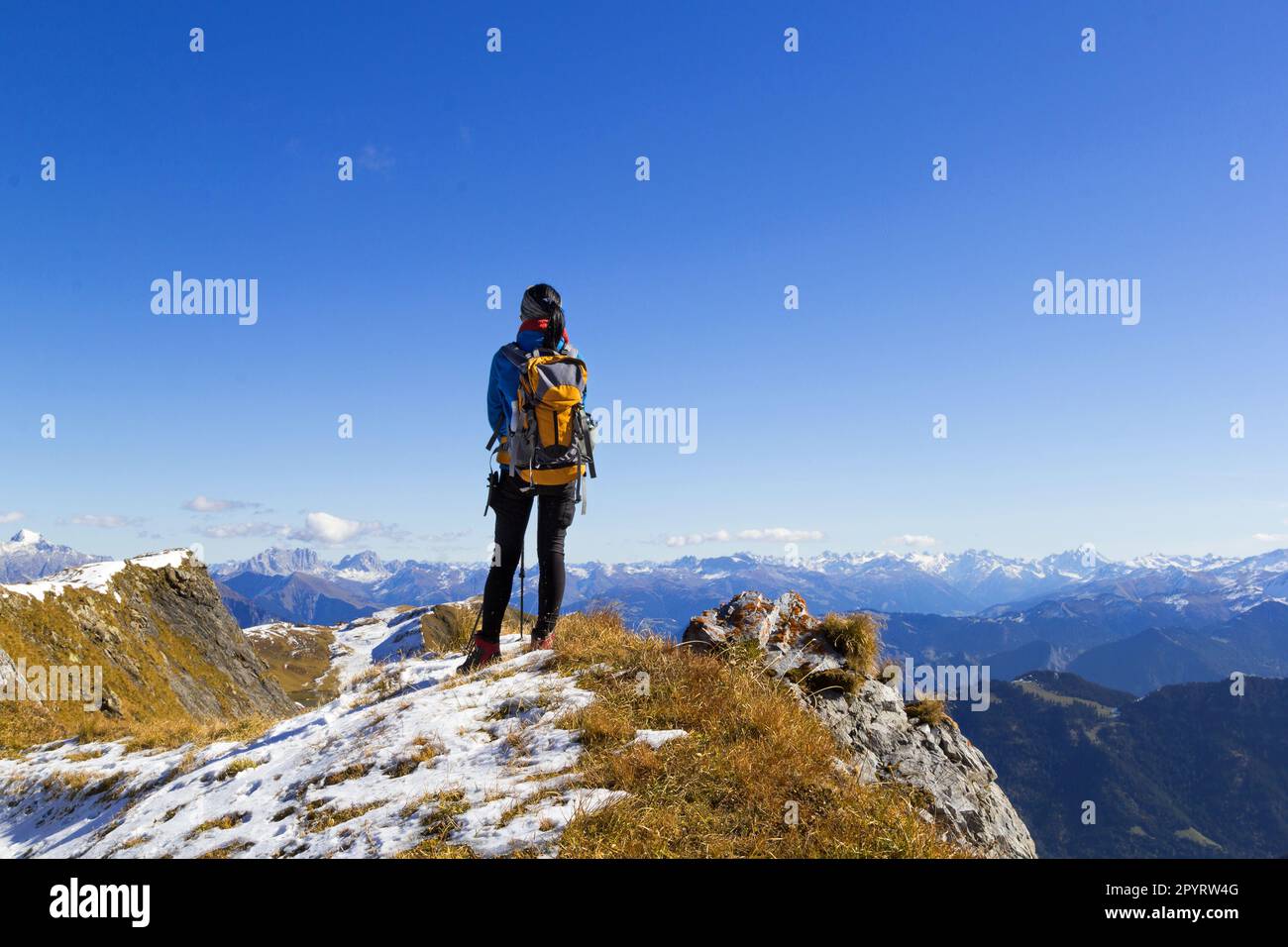 Rückblick auf eine Wanderin auf dem Berggipfel, die die AIPs unter dem blauen, sonnigen Himmel beobachten kann Stockfoto