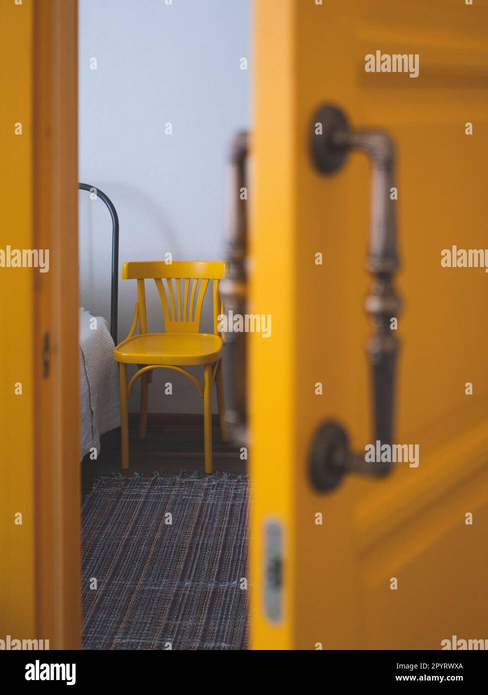 Bettrand und ein Stehstuhl von einer halb offenen Tür, selektiver Fokus. Konzept der Betreuung bettreibender Patienten Stockfoto