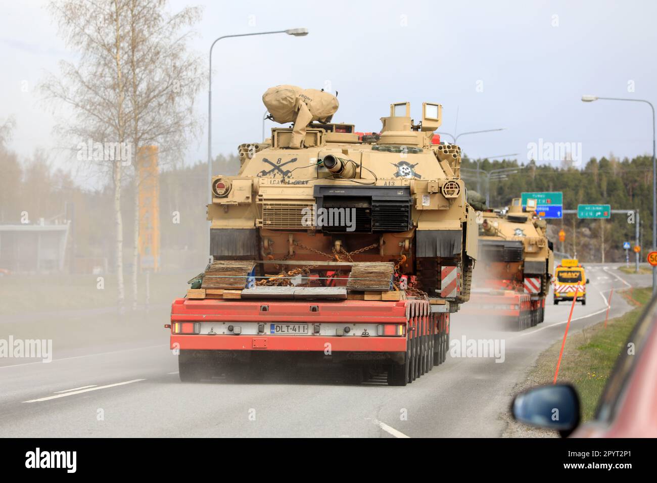 Transporter transportieren amerikanische M1 Abrams Militärpanzer im Verkehr. Konvoi mit drei übergroßen Ladungstransporten auf der Straße. Salo, Finnland. 28. April 2023. Stockfoto