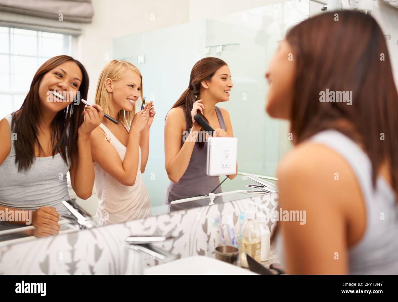 Schöne Damen, die sich anfreunden. Drei Freunde schminken sich vor dem Spiegel. Stockfoto