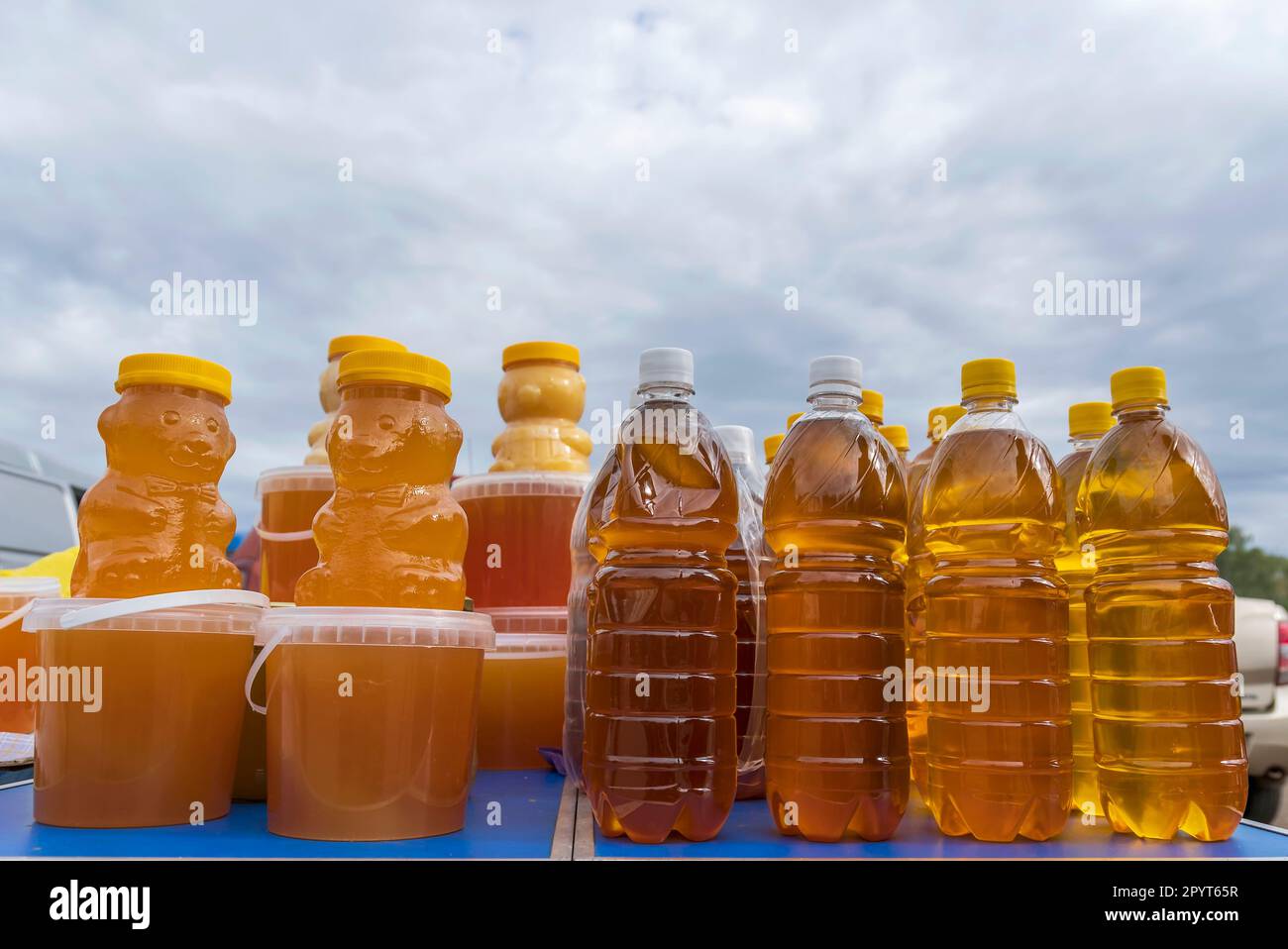 Landwirtschaftsmesse im Herbst. Kunststoffbehälter mit Bienenhonig und Flaschen Sonnenblumenöl Stockfoto