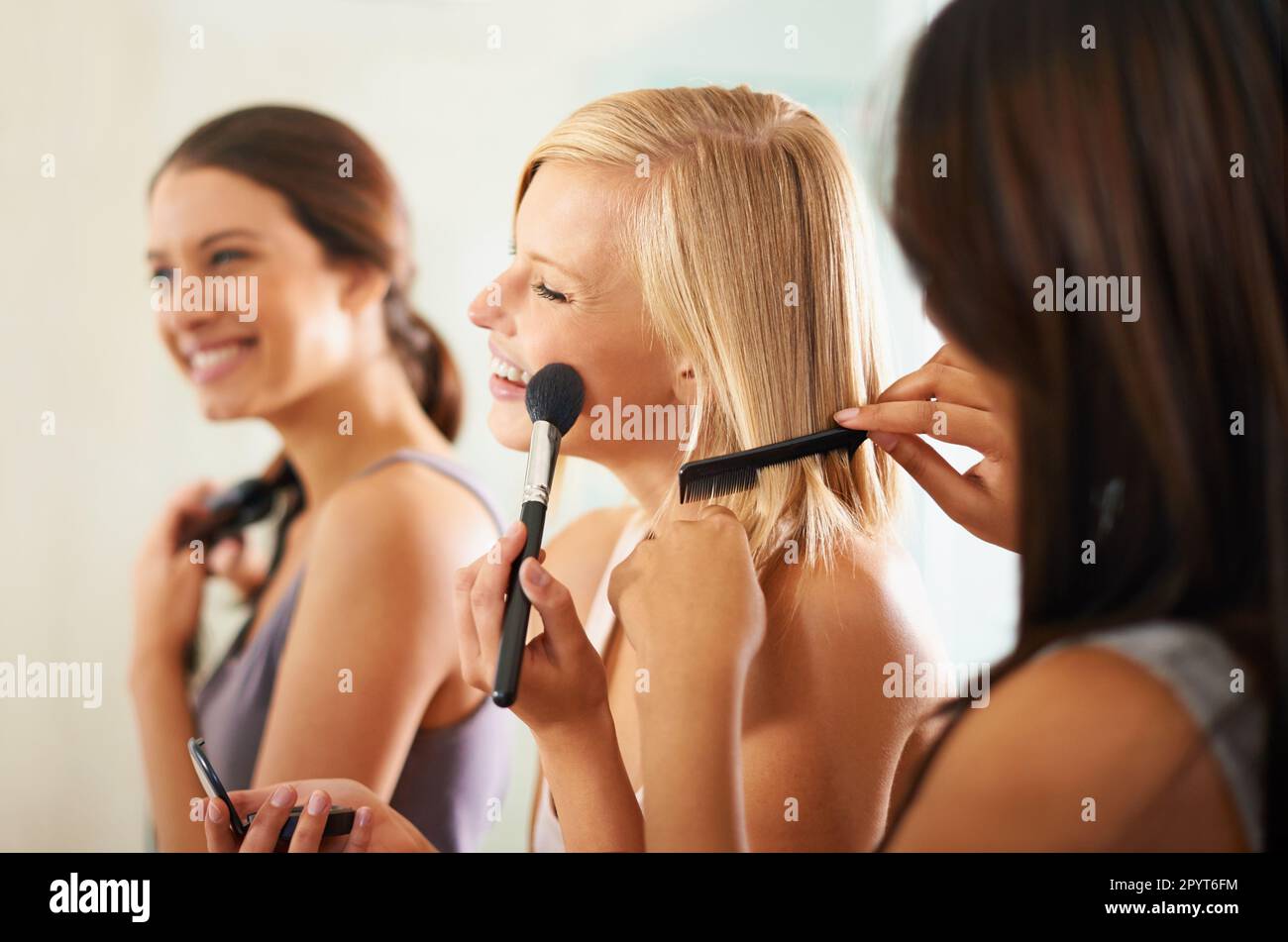 Wir fühlen uns hübsch. Drei Freunde schminken sich und stylen ihr Haar zusammen. Stockfoto