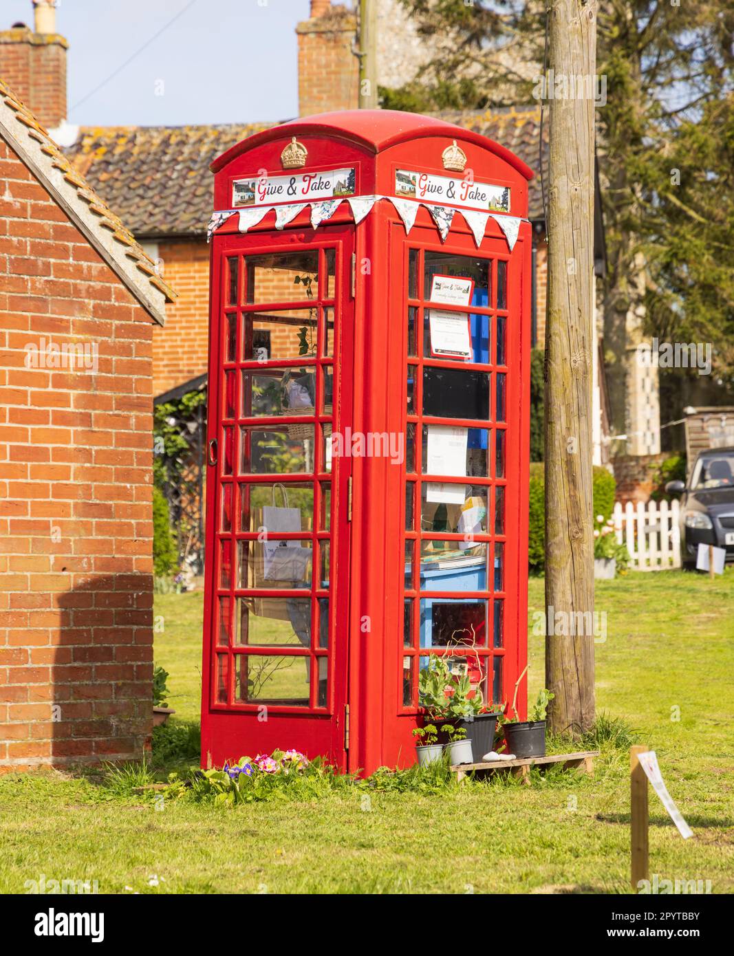 Alte öffentliche rote Telefonzelle, die als Drehscheibe für den freien Austausch unerwünschter Bücher, Lebensmittel, Pflanzen und Spielzeug genutzt wird. Middleton, Suffolk, Großbritannien Stockfoto