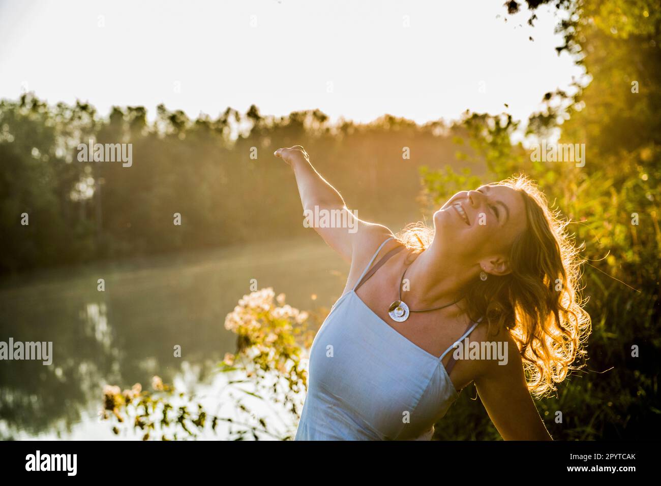 Eine glückliche, schöne Frau, die draußen am Fluss nach oben schaut Stockfoto
