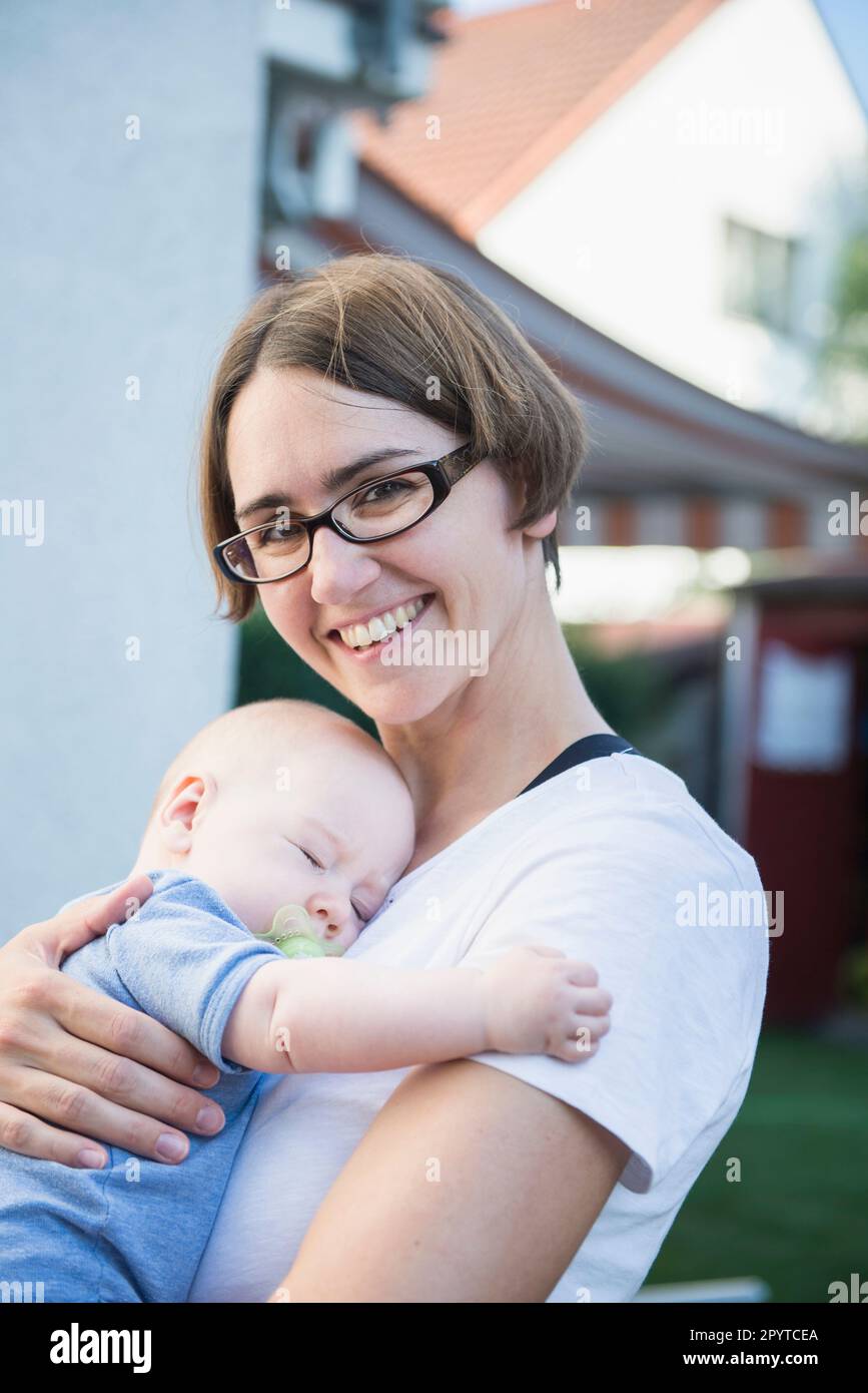 Mutter umarmt das schlafende Baby in ihren Armen, Bayern, Deutschland Stockfoto