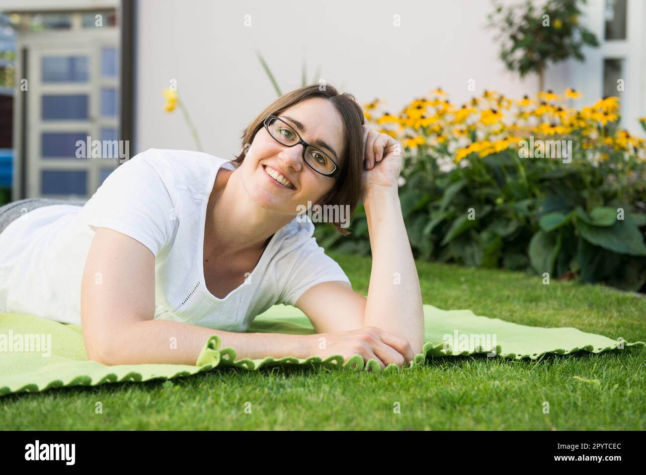 Porträt einer Frau, die auf einer Decke im Garten ihres Hauses liegt, Bayern, Deutschland Stockfoto