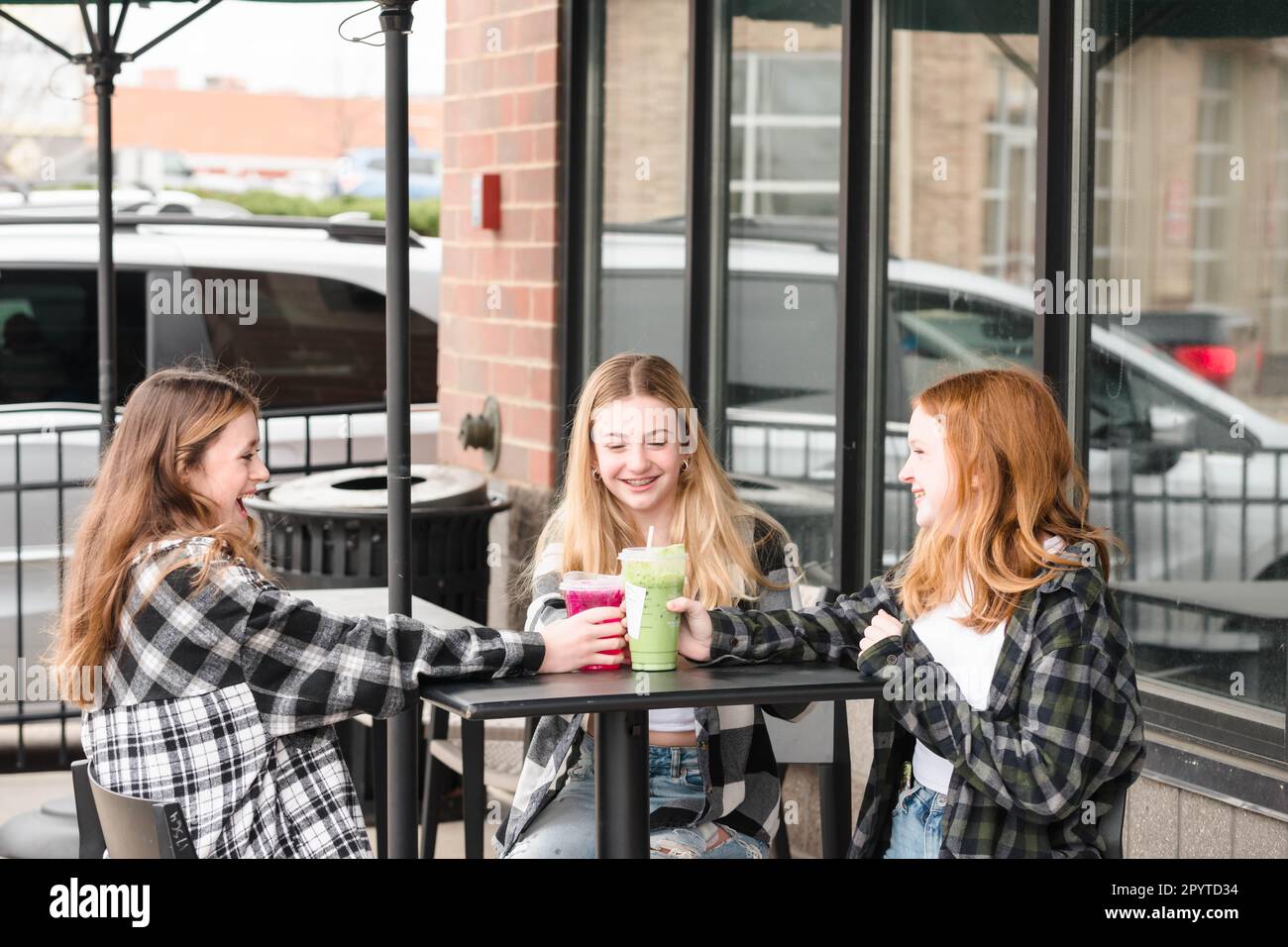 Drei glückliche Teenager-Mädchen, die vor einem Café was trinken. Stockfoto
