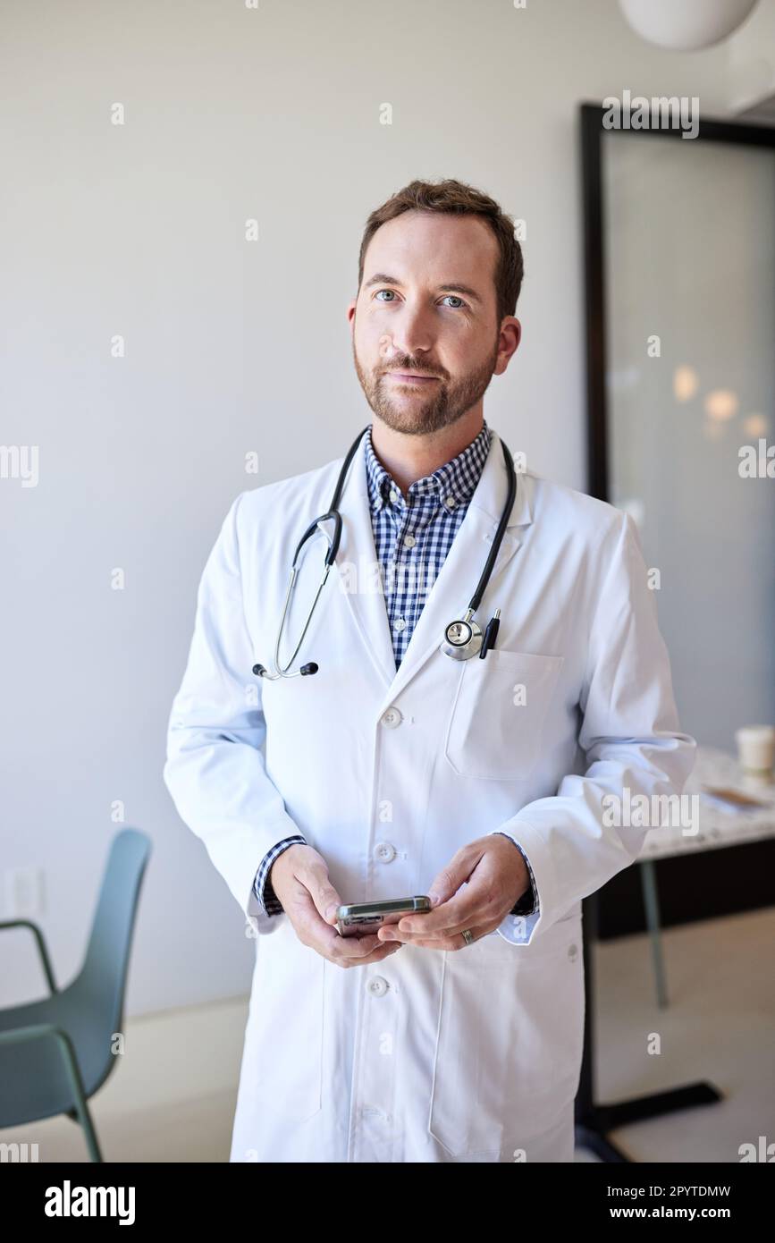 Porträt eines männlichen Gesundheitspersonals, der Laborkittel trägt, während er steht Stockfoto