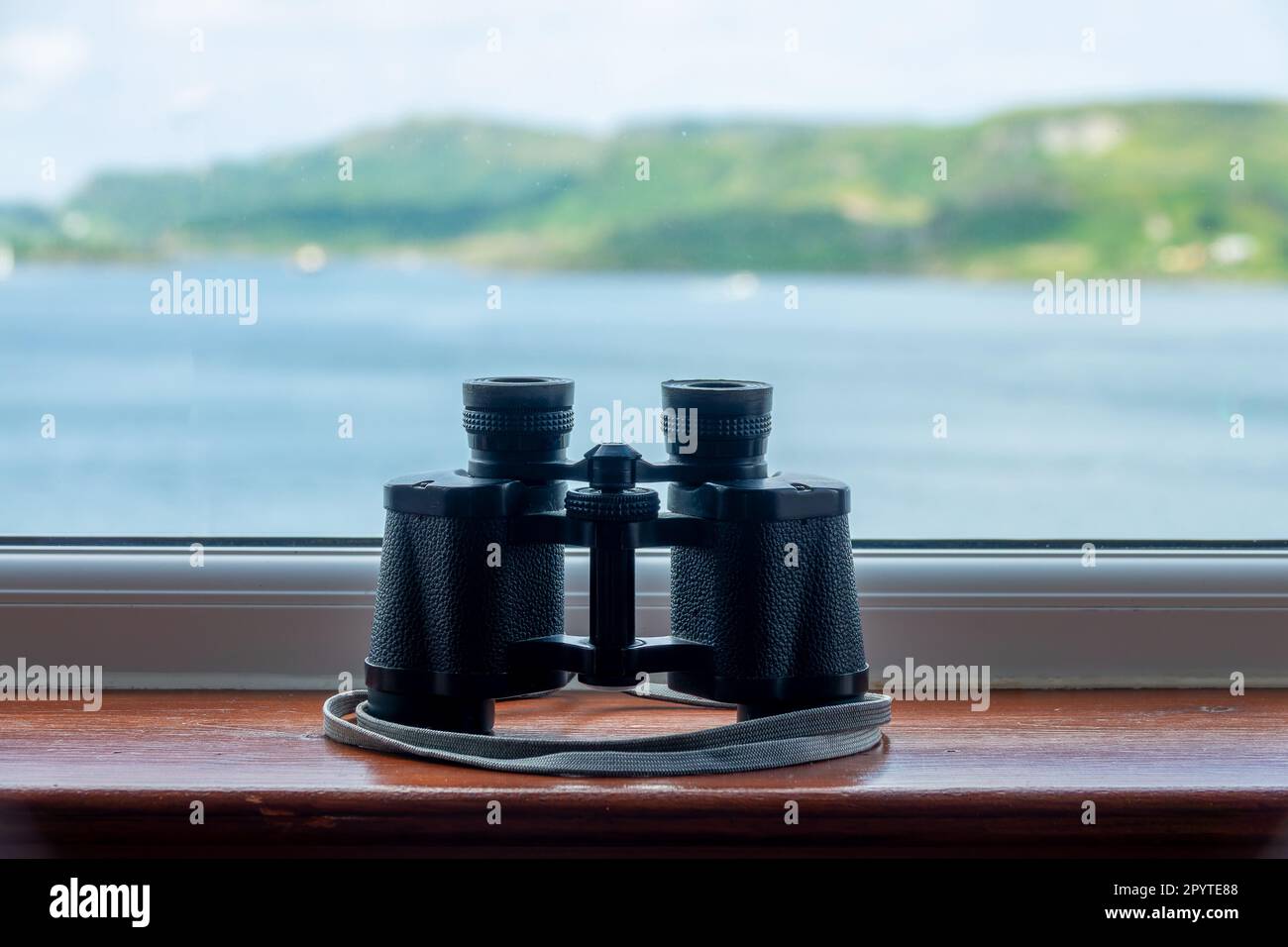 Retro-Ferngläser im Vintage-Stil auf einer Fensterbank mit Meerblick in Schottland, Großbritannien Stockfoto