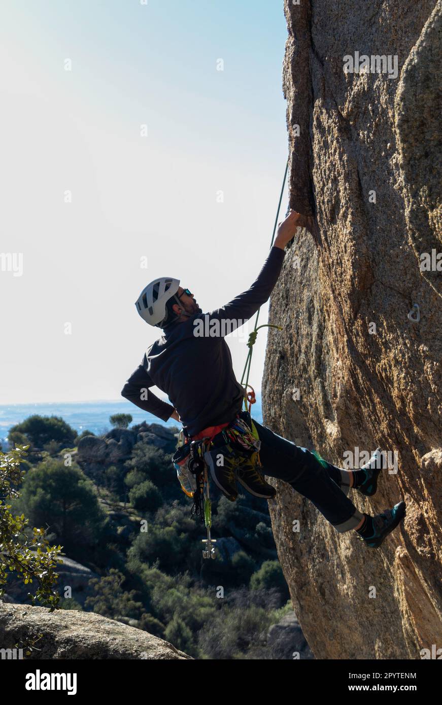 Junger Erwachsener klettert auf eine Granitmauer in Torrelodones, Madrid. Felsklettern. Extremsportkonzept Stockfoto