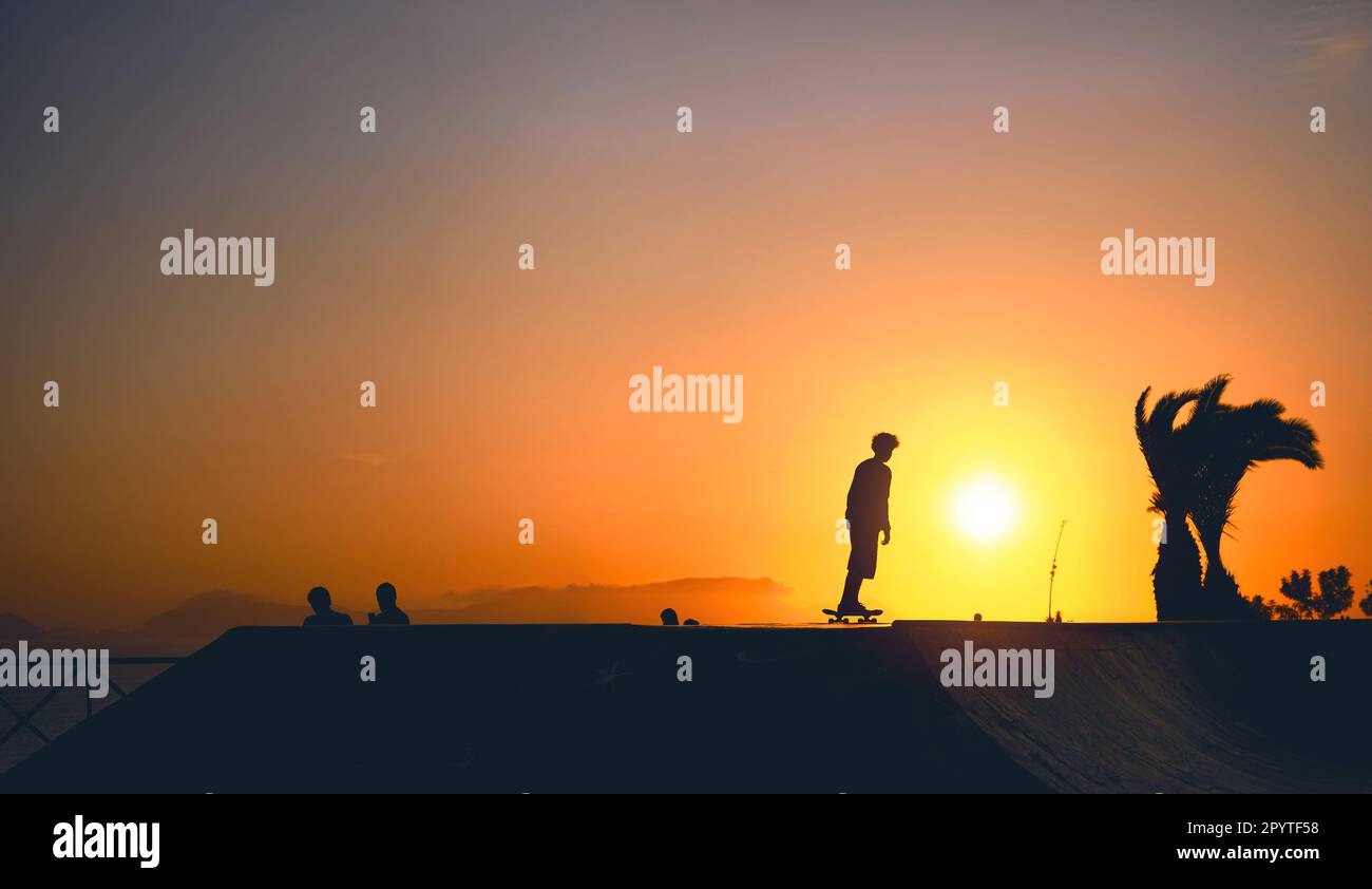 Ein Gruppenjunge auf Skateboard im Sommer, die Silhouette ist nicht zu erkennen. Stockfoto