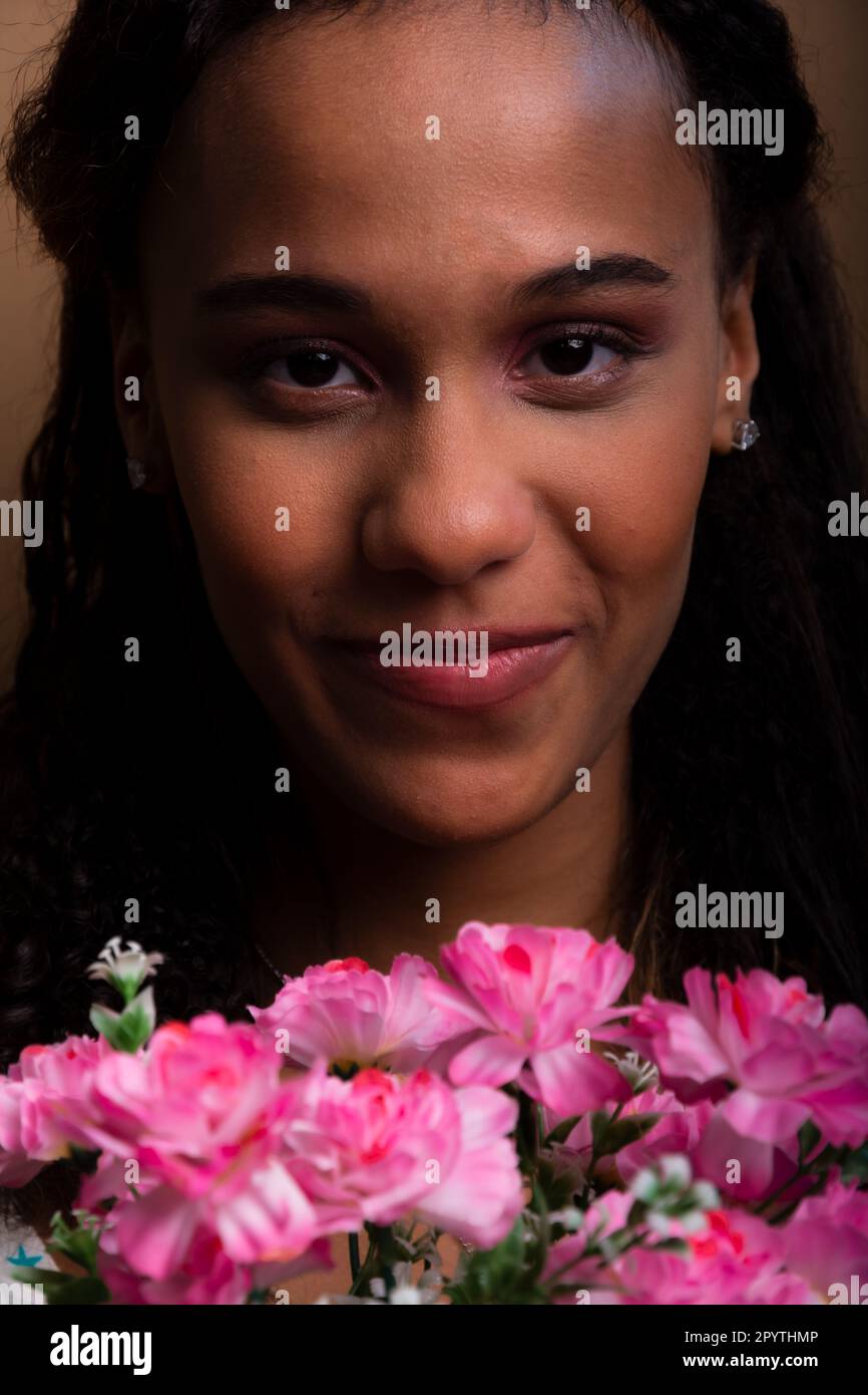 Nahaufnahme eines hübschen Teenagers mit Blumenstrauß. Isoliert auf braunem Hintergrund. Stockfoto