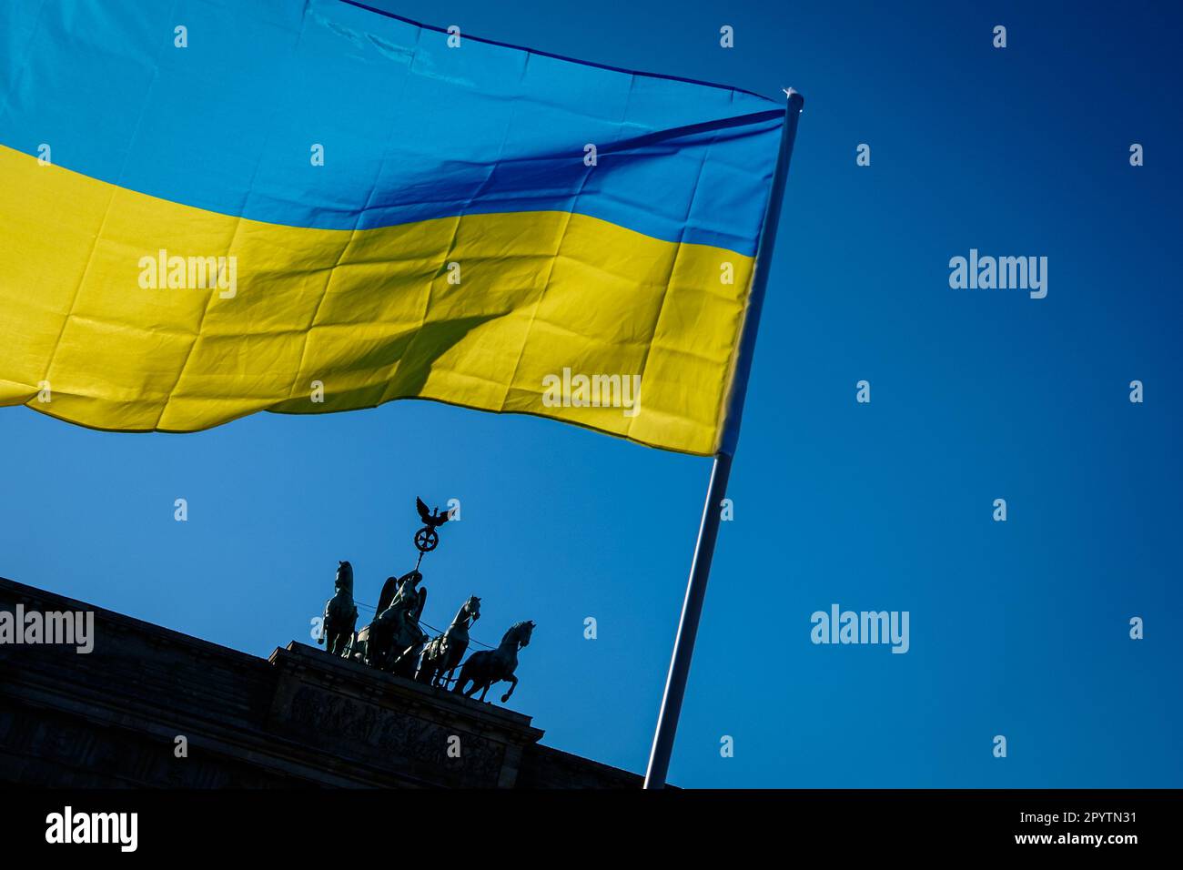"Deutschland, Berlin, 13. März 2022: Die ukrainische Flagge ist vor dem Brandenburger Tor zu sehen, während sich Zehntausende unter dem Slogan "Stopp den Krieg" versammeln. Frieden und Solidarität für das ukrainische Volk'' vom Alexanderplatz bis zur Straße des 17. Juni in der Mitte Berlins.' Stockfoto