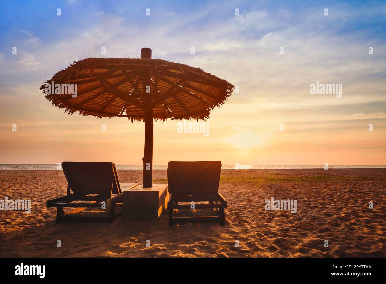 Strandurlaub, zwei Sonnenliegen und Sonnenschirm, Urlaub Reisehintergrund, Sommeruntergang. Stockfoto Strandurlaub, zwei Sonnenliegen und Sonnenschirm, Urlaub Reisehintergrund, Sommeruntergang. Stockfoto